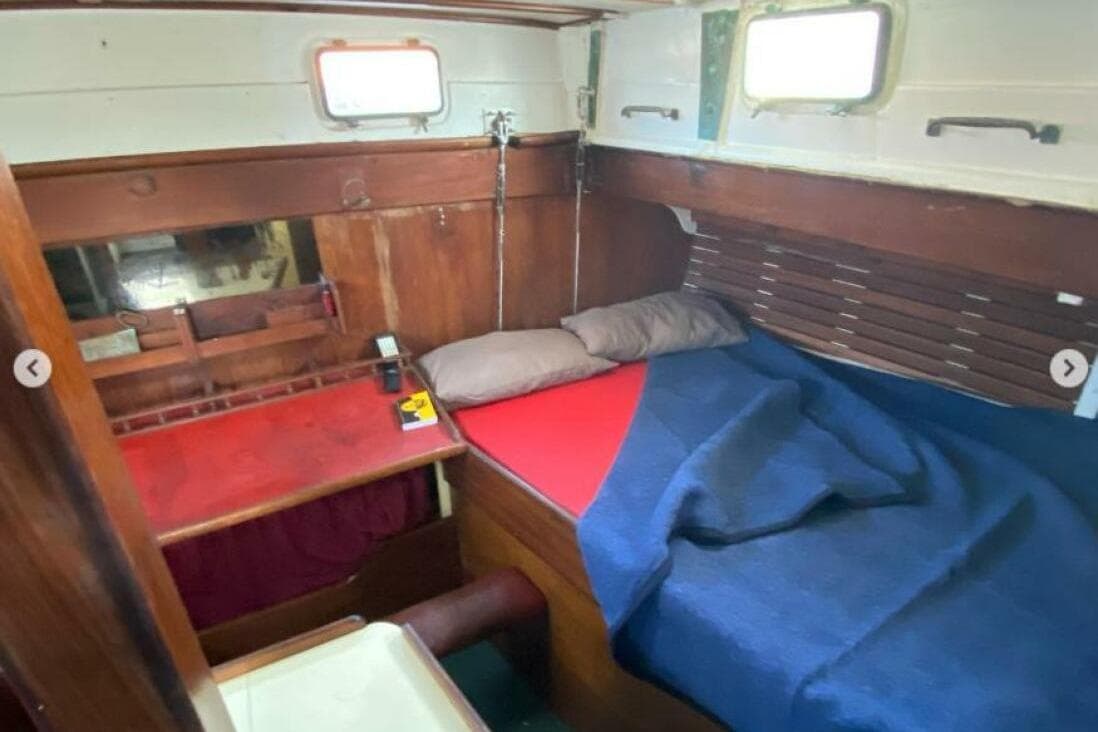 Cozy 1966 Custom boat cabin with wooden interior, bed, and desk.