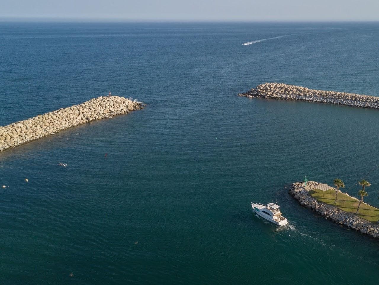 Aerial view of 2005 Riviera 47 Convertible Series II yacht exiting marina into open sea.