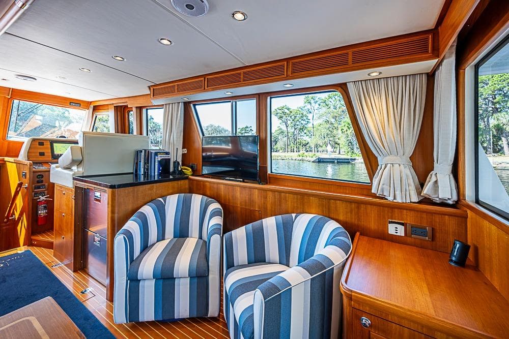 Luxurious interior of 2013 Grand Banks 43 Europa yacht with striped chairs and scenic window view.