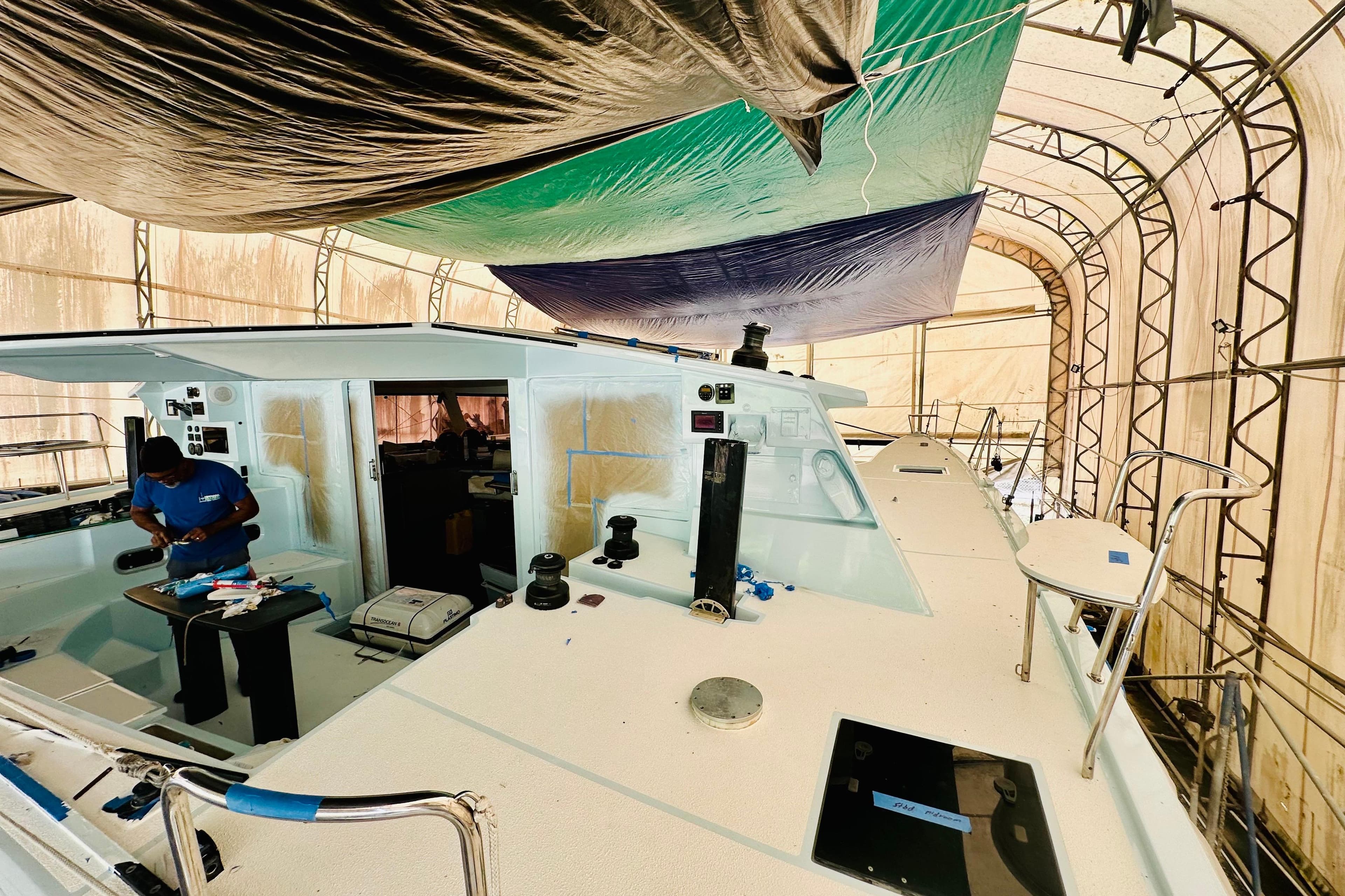 Worker refurbishing 2011 Alibi 54 yacht under protective canopy.