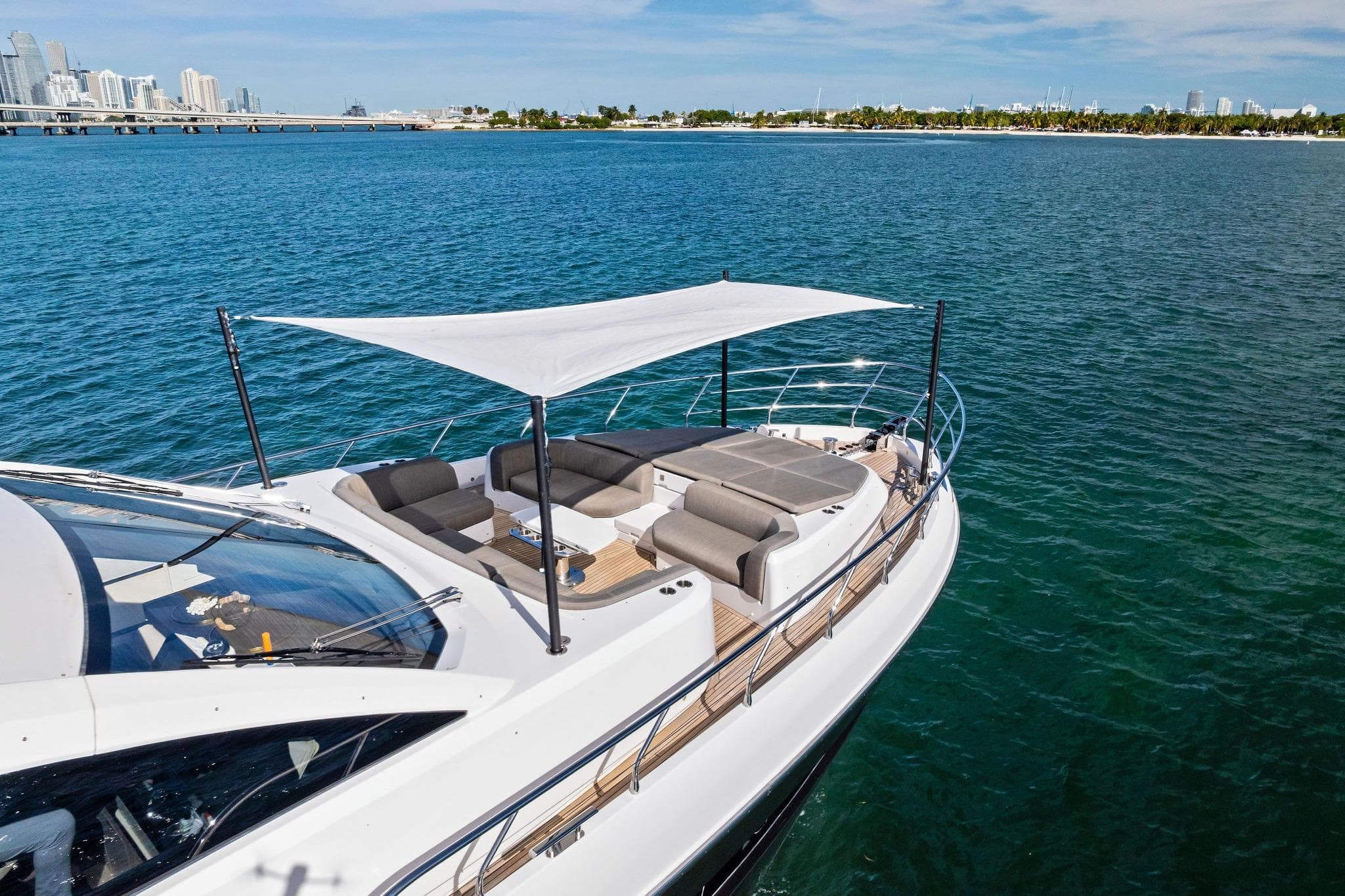 Luxurious 2021 Azimut Fly 78 yacht with sunshade, cruising near city skyline.