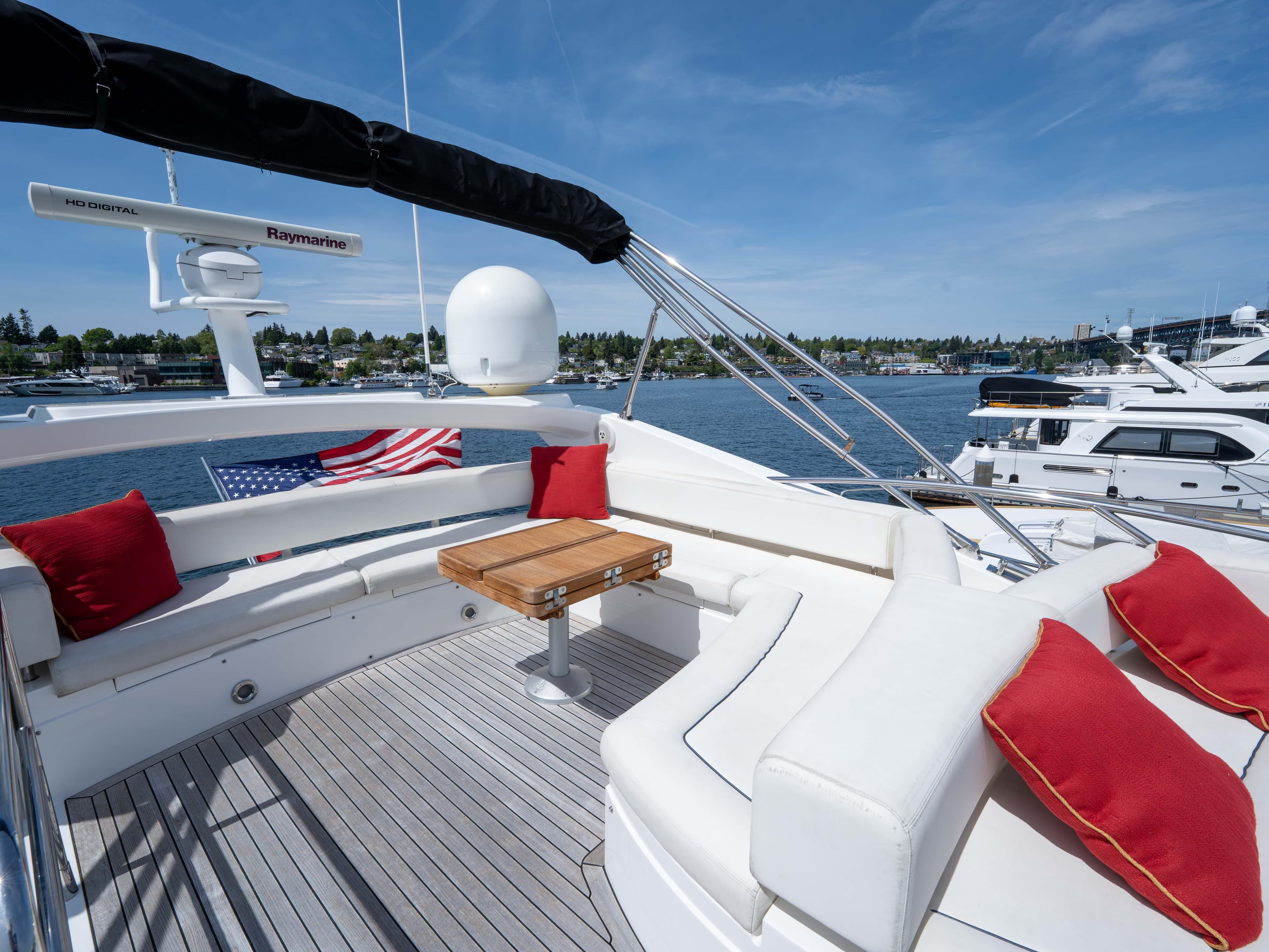 Luxurious Sunseeker Manhattan 63 yacht deck with seating, table, and scenic waterfront view.