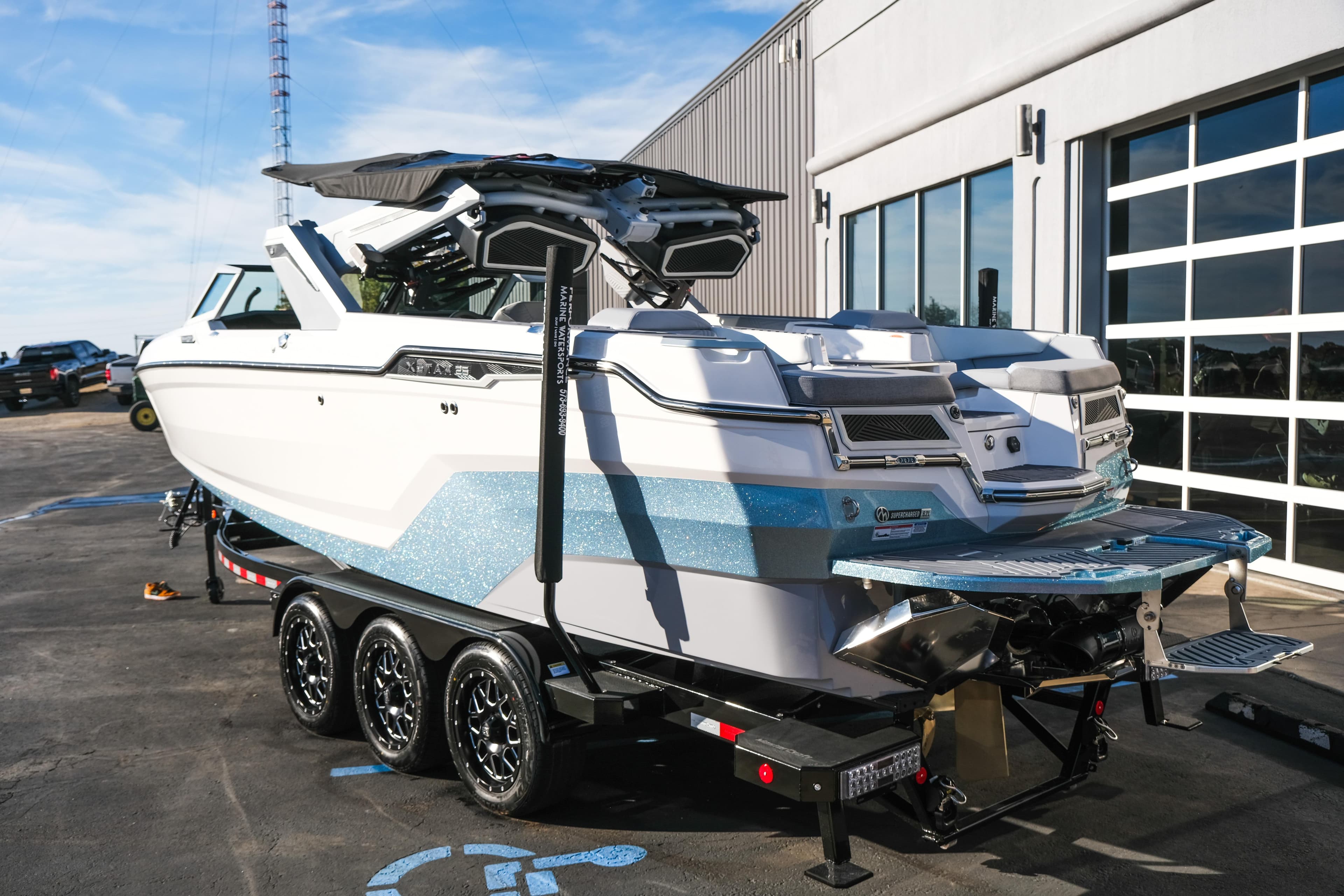 2026 MasterCraft XStar 25 boat on trailer, parked outside a modern building.