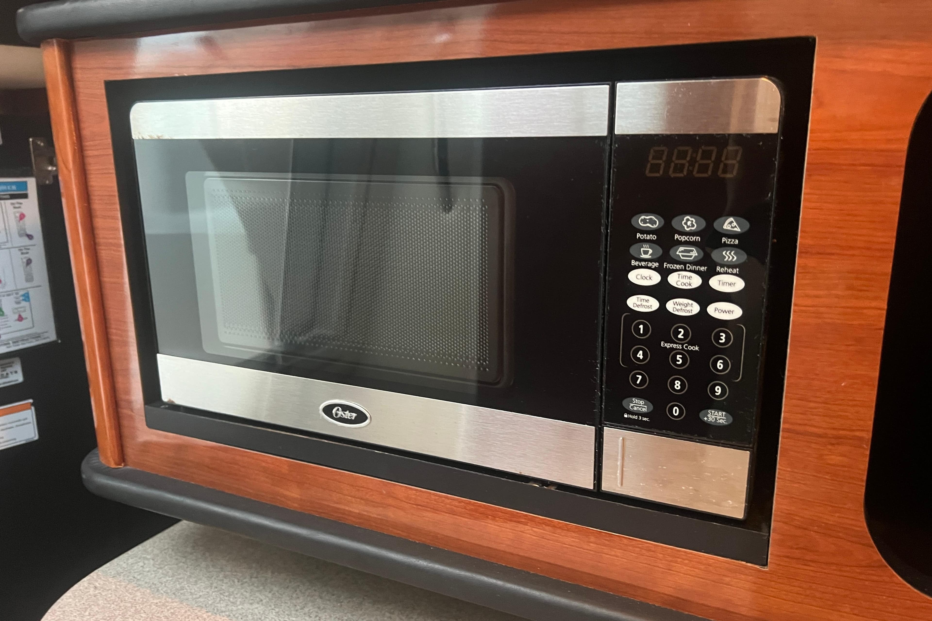 Microwave oven inside 2007 Sea Ray 260 Sundancer boat, featuring digital controls and wood paneling.