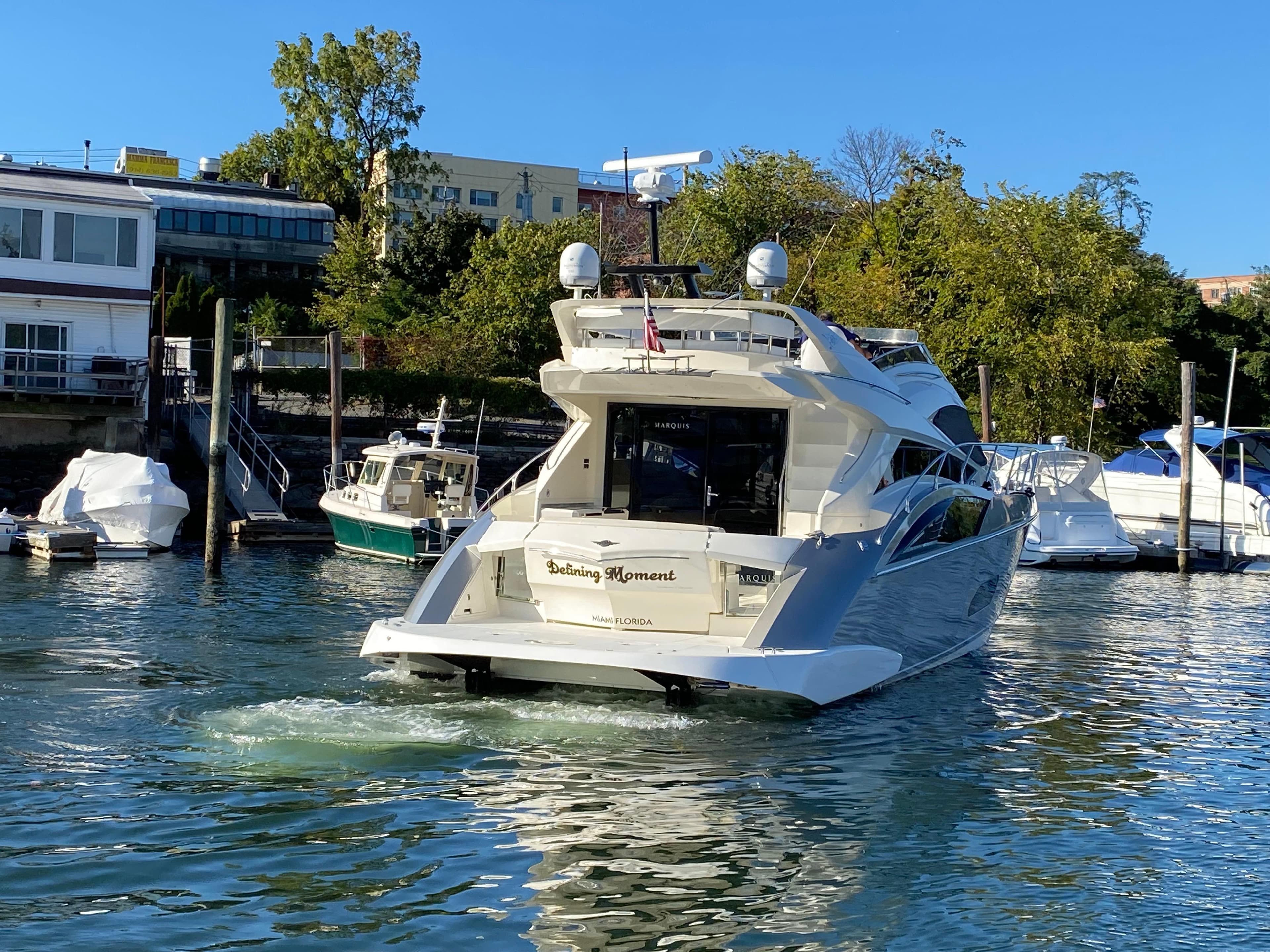 2010 Marquis 500 Sport Bridge yacht docked in a marina, surrounded by other boats.