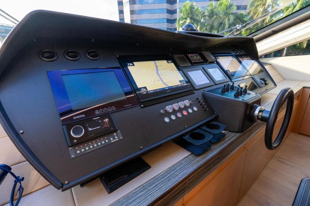 Control panel of a 2012 Pershing 92 yacht with navigation screens and steering wheel.