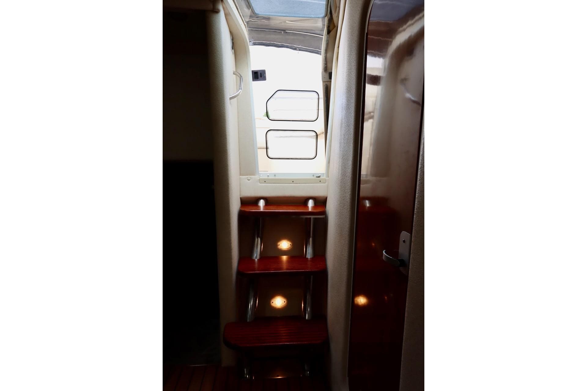 Interior stairs of 2006 Rinker 360 Express Cruiser with wooden steps and lighting.