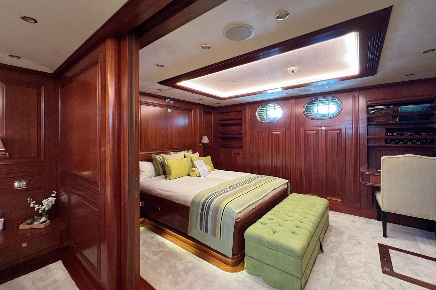 Luxurious yacht bedroom with wood paneling, elegant bedding, and ambient lighting on Custom-Craft Steel Pax Navi.
