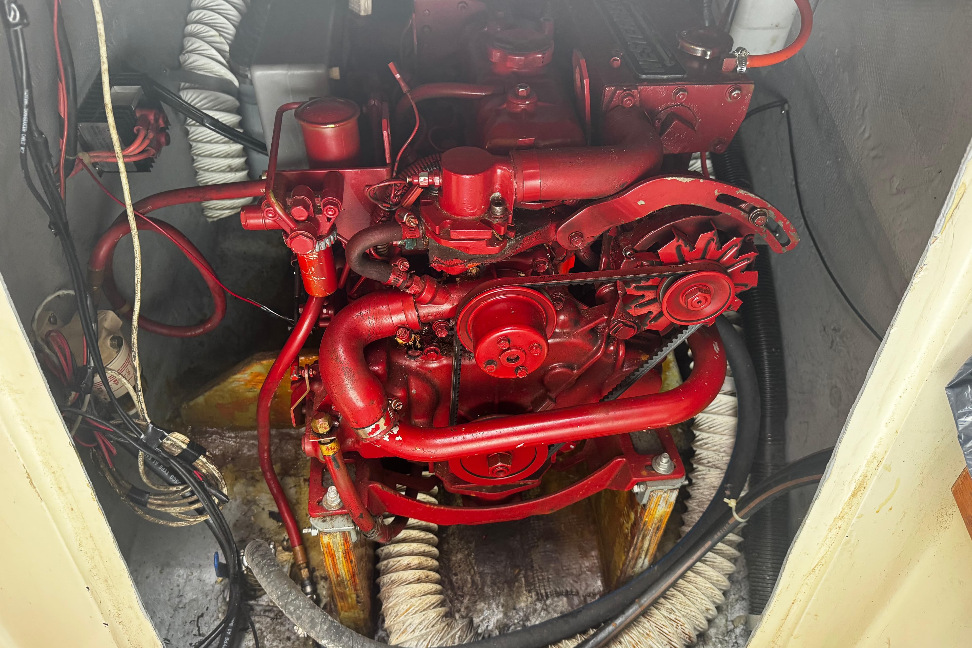 Red engine inside a 1984 Nonsuch 26 Classic sailboat, showcasing mechanical components and wiring.