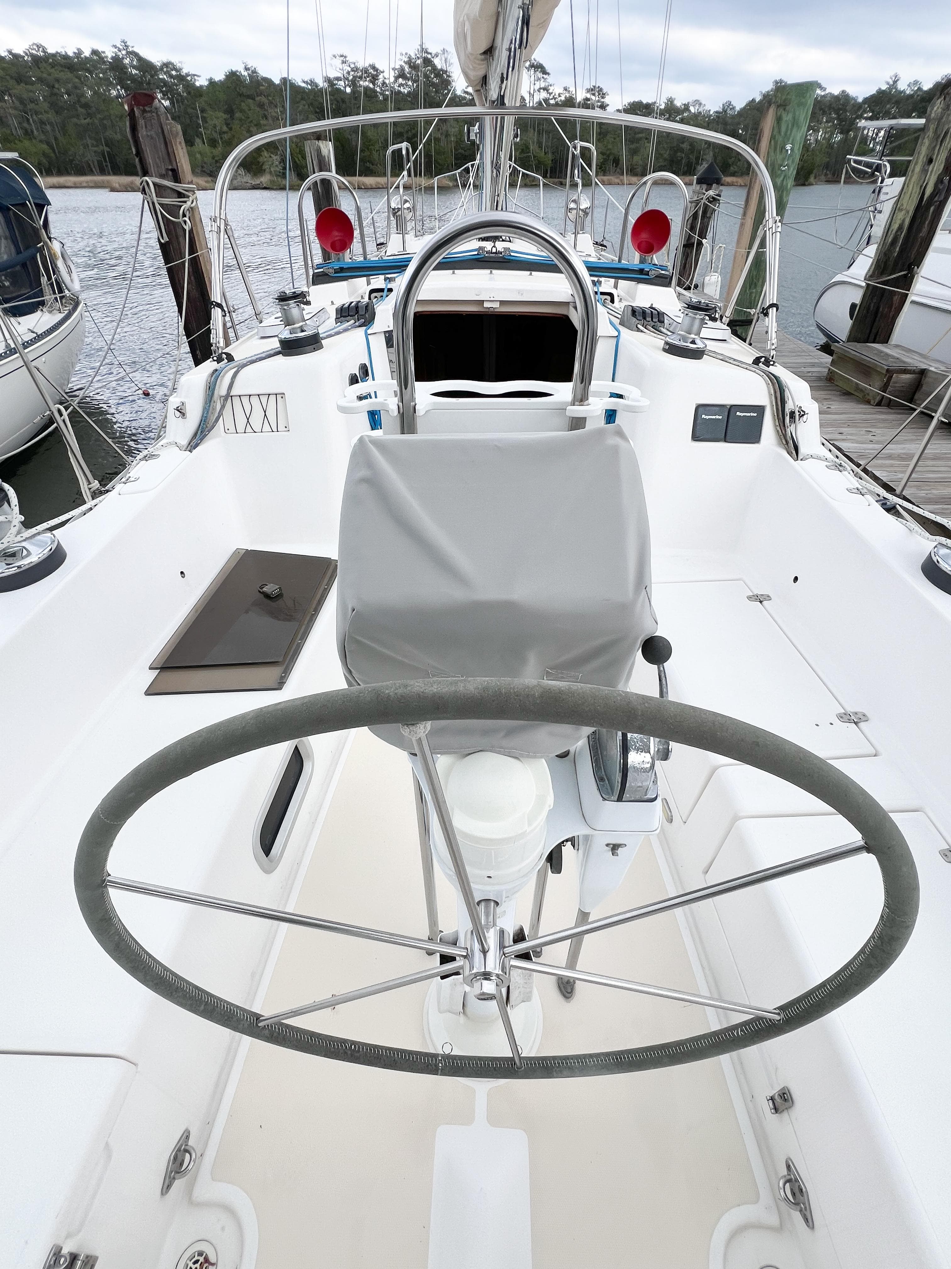 Cockpit of 1998 Saga 43 sailboat with steering wheel and marina background.