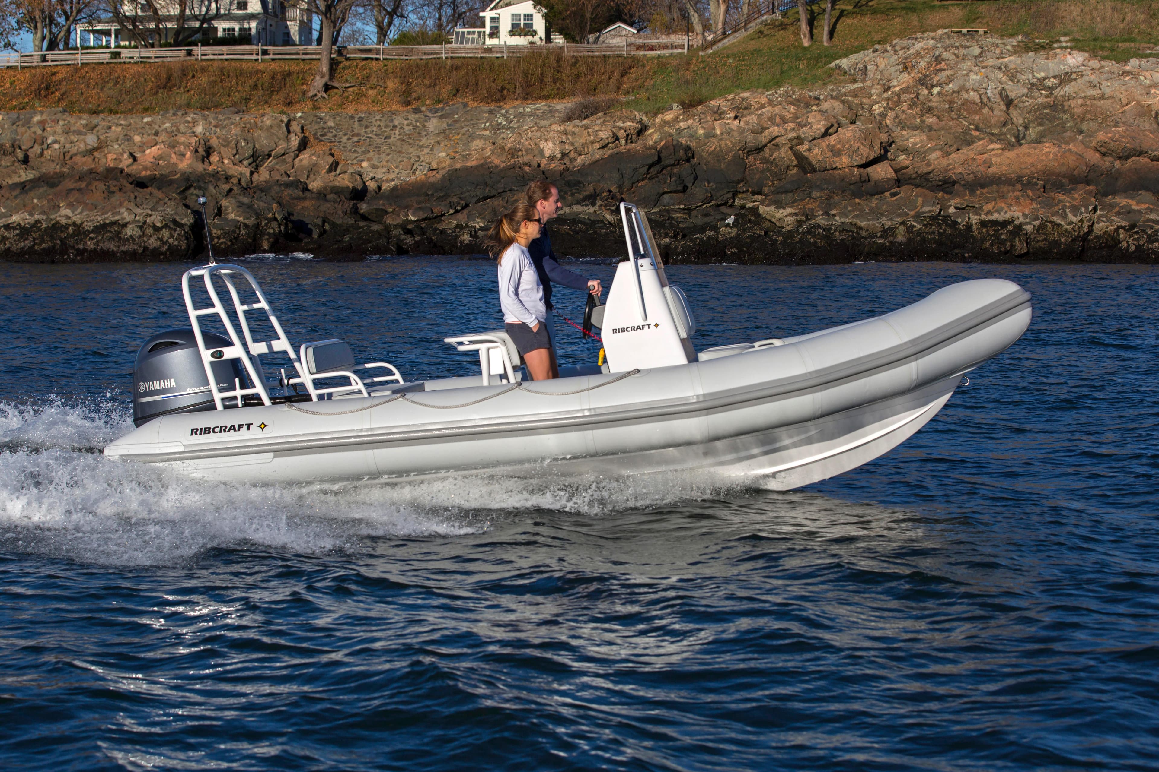 2024 Ribcraft 5.85 boat cruising on water near rocky shoreline.