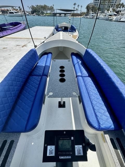2023 Vision Marine Technologies Fantail 217 boat with blue seating, docked by the water.