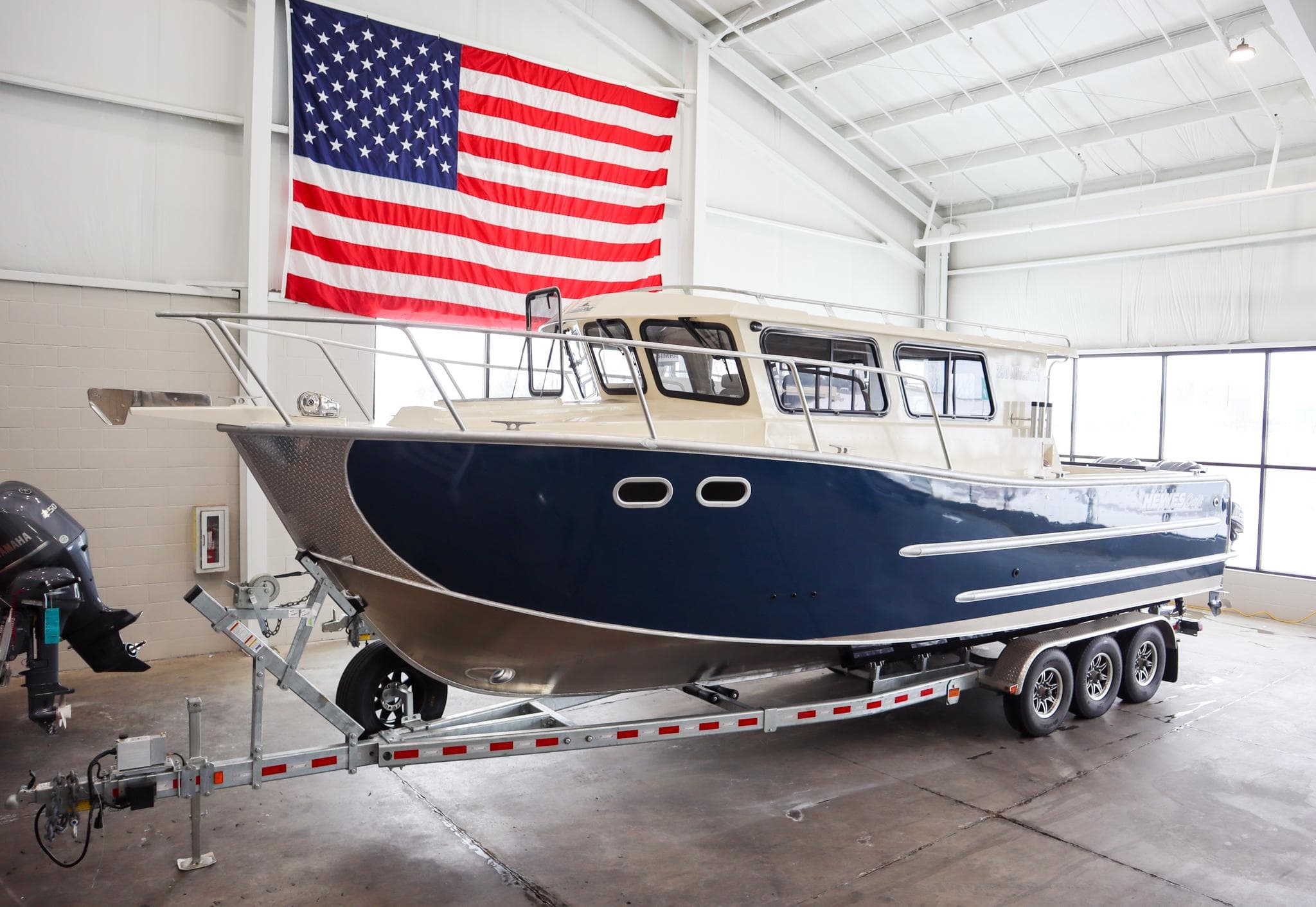 2025 Hewescraft 290 Adventure ET HT boat on trailer in warehouse with American flag.