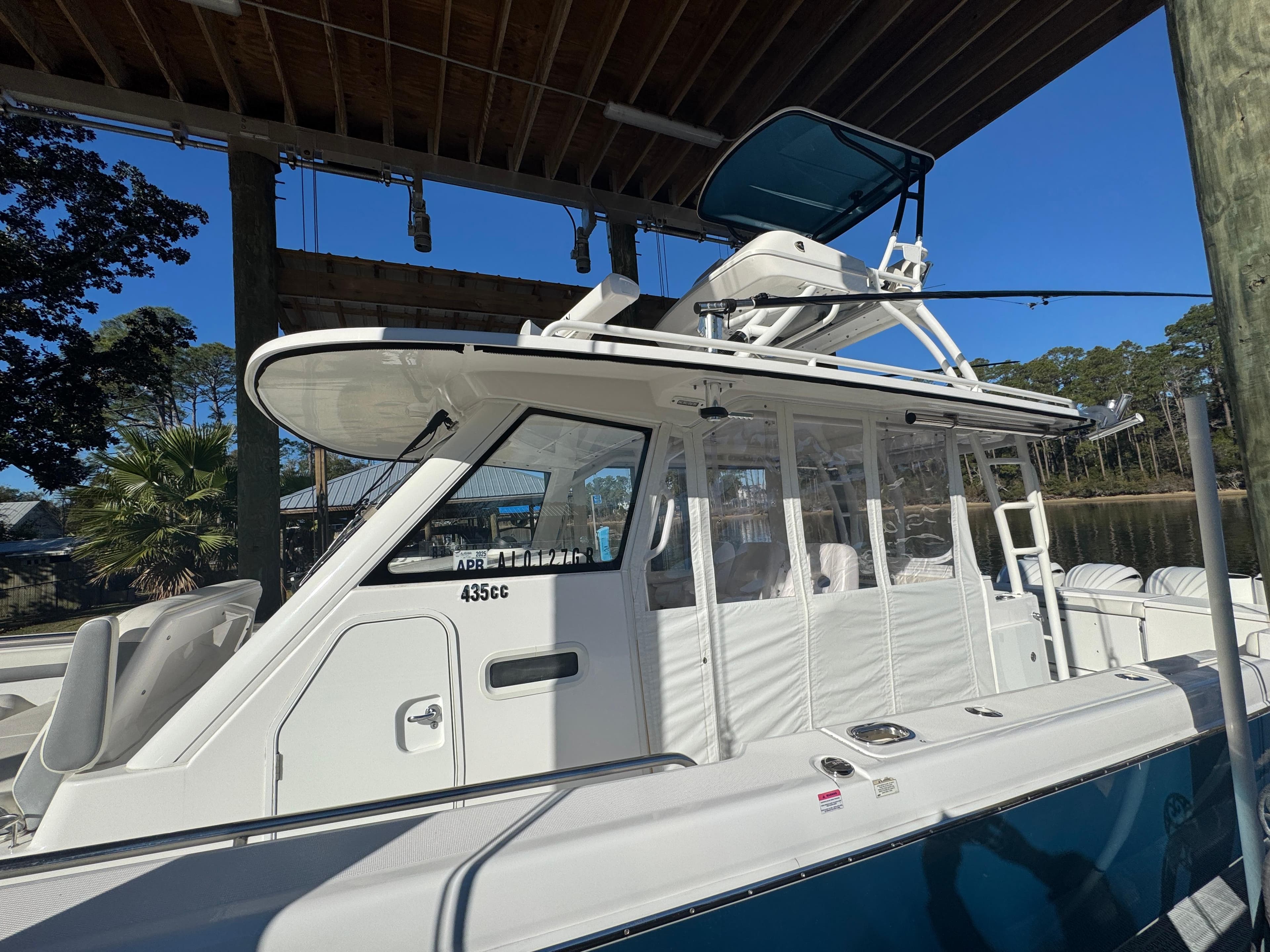 2016 Everglades 435 Center Console boat docked under a wooden canopy.