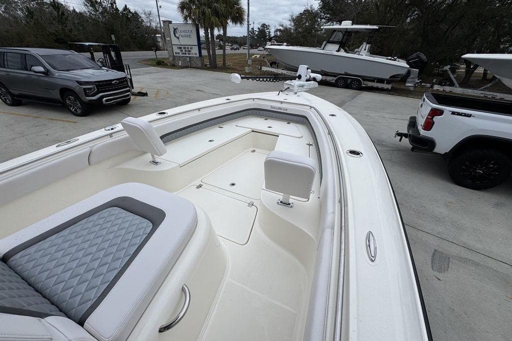 2026 ShearWater 260 Carolina Flare boat with spacious seating, parked near vehicles.