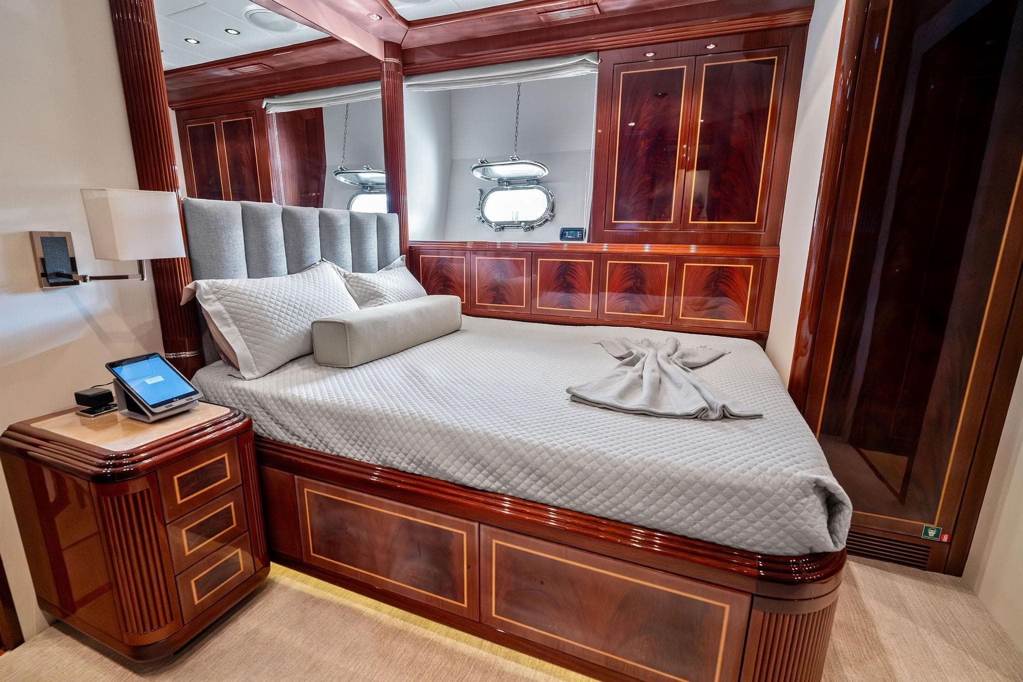 Luxurious bedroom interior on 2005 Mangusta 130 yacht, featuring elegant wood paneling and plush bedding.