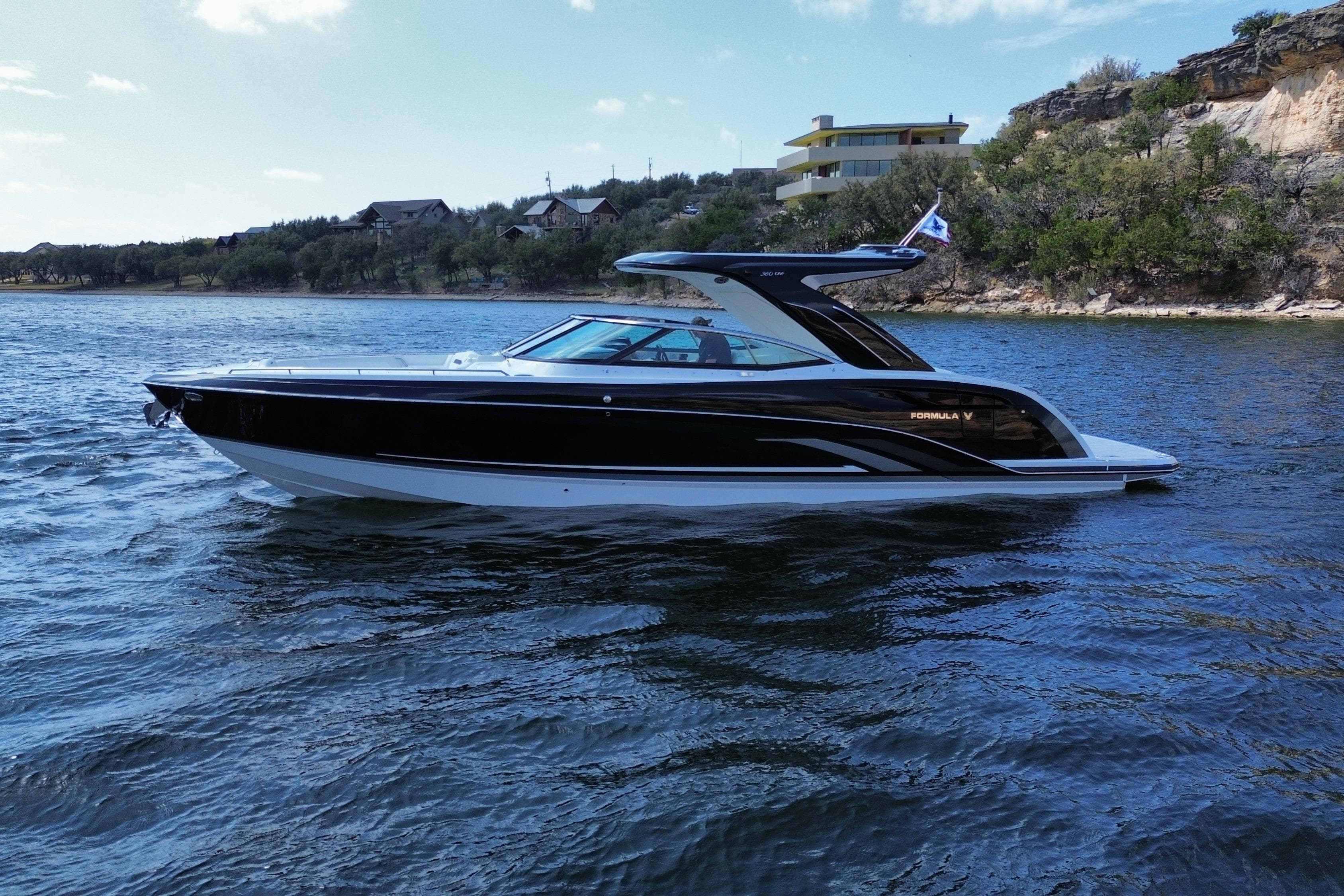 2026 Formula 360 Crossover Bowrider I/O on scenic lake with modern architecture backdrop.