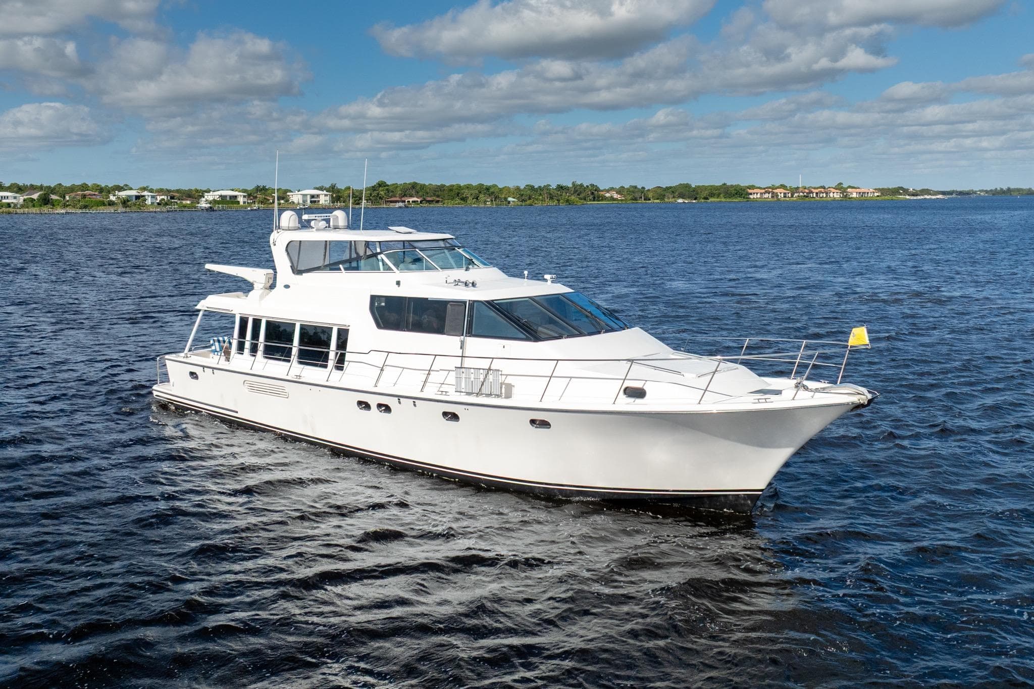 2009 Pacific Mariner 65 Motoryacht cruising on a serene blue lake under a partly cloudy sky.