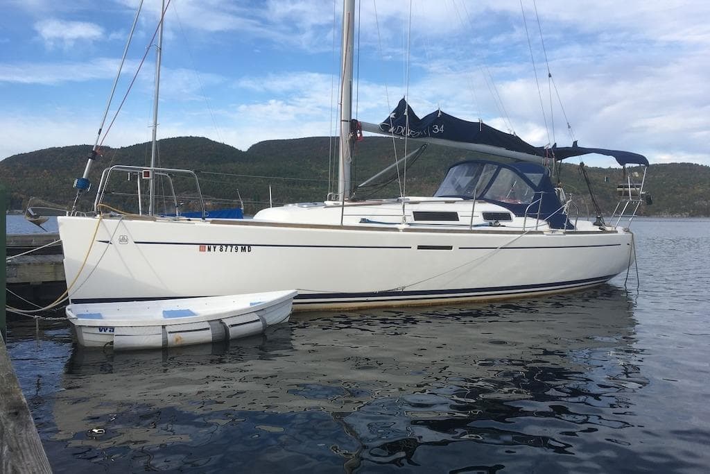 2004 Dufour 34 Performance sailboat docked on calm water with scenic mountain backdrop.