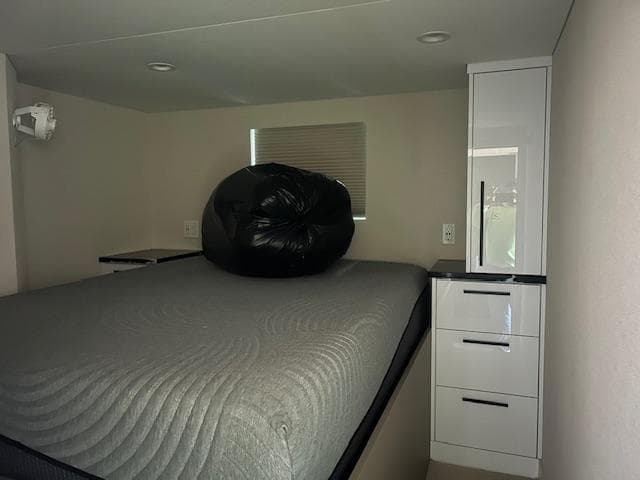 Interior of 2023 Adonia Ovation RV with bed and storage cabinet.
