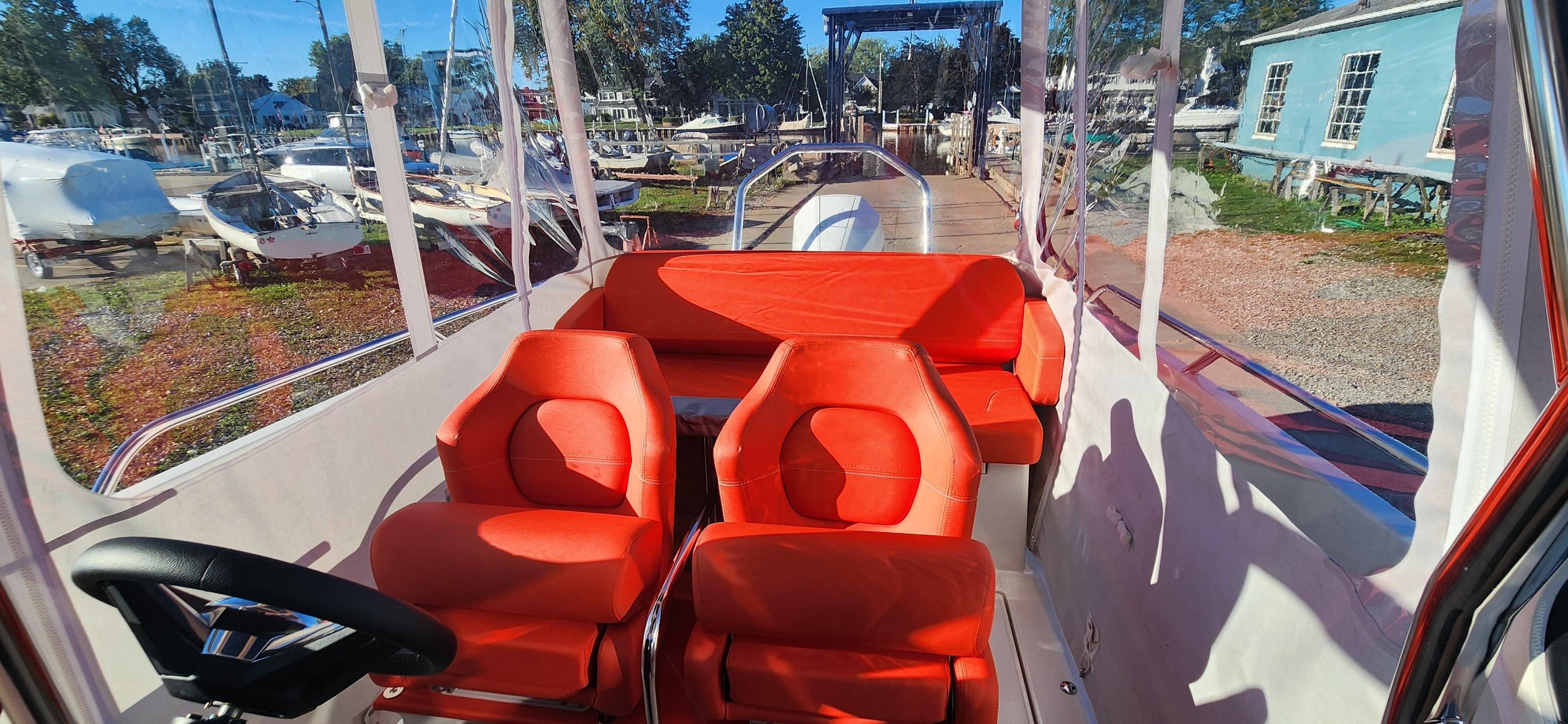 Interior of 2023 Nimbus T8 boat with vibrant red seating and clear windows.