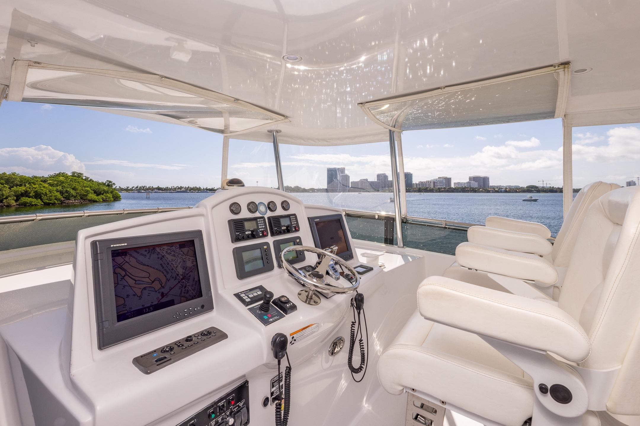 Helm of 2009 Hatteras 64 Motor Yacht with navigation screens and white seating.