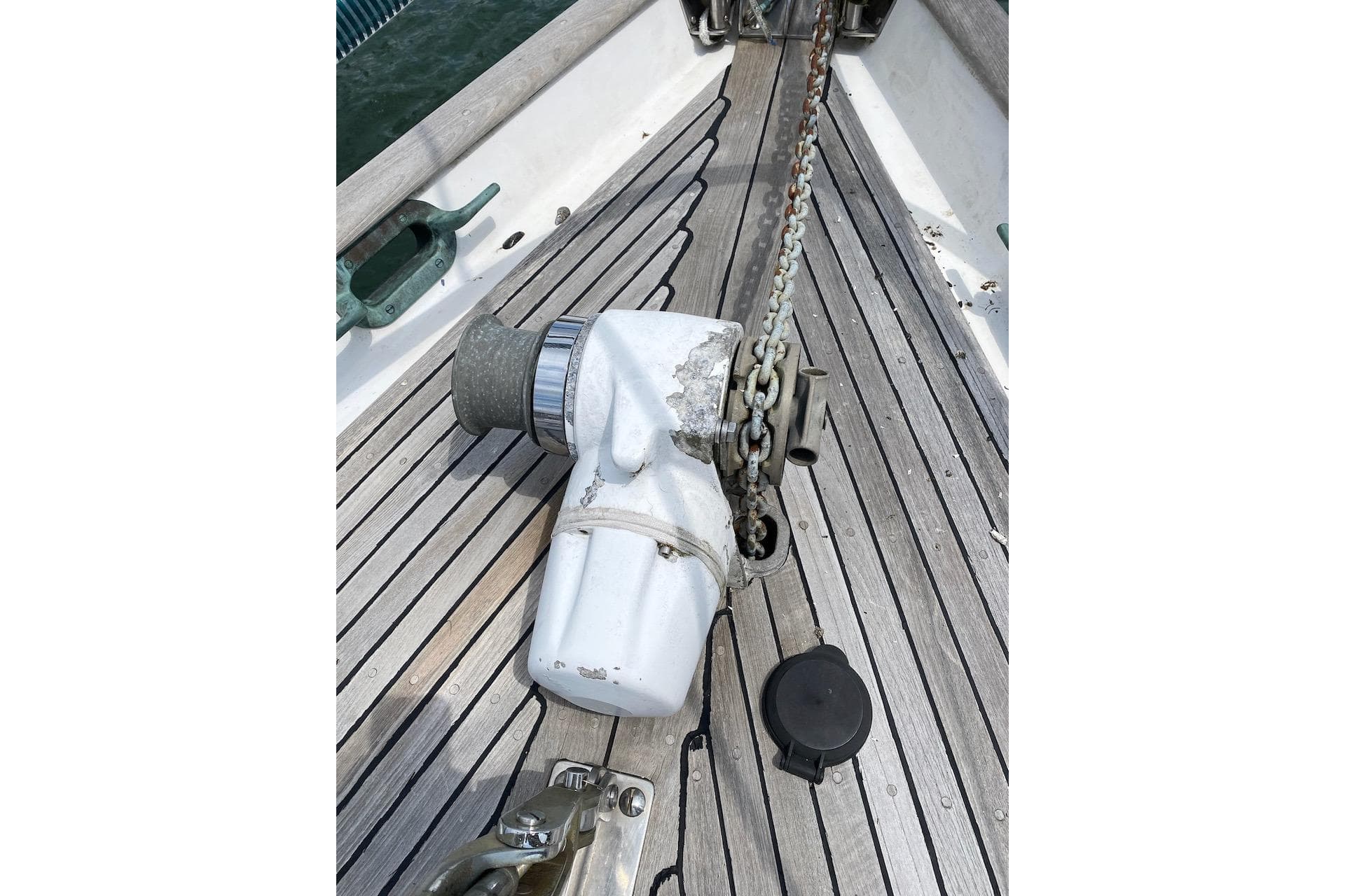Anchor windlass on 1985 Liberty 458 sailboat deck with wooden planks.