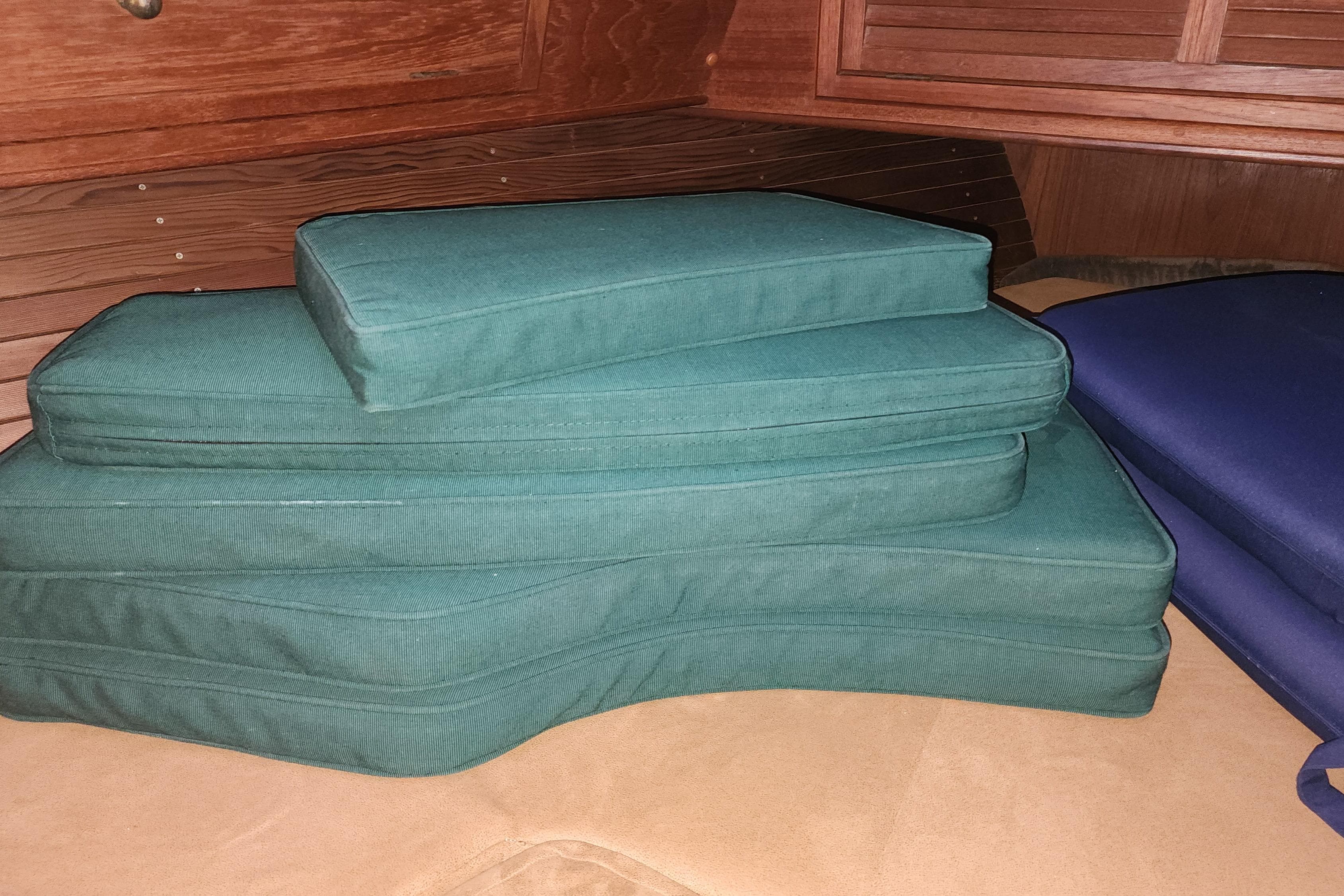 Green and blue cushions stacked inside a 1986 Saturna 33 Pilot boat cabin.