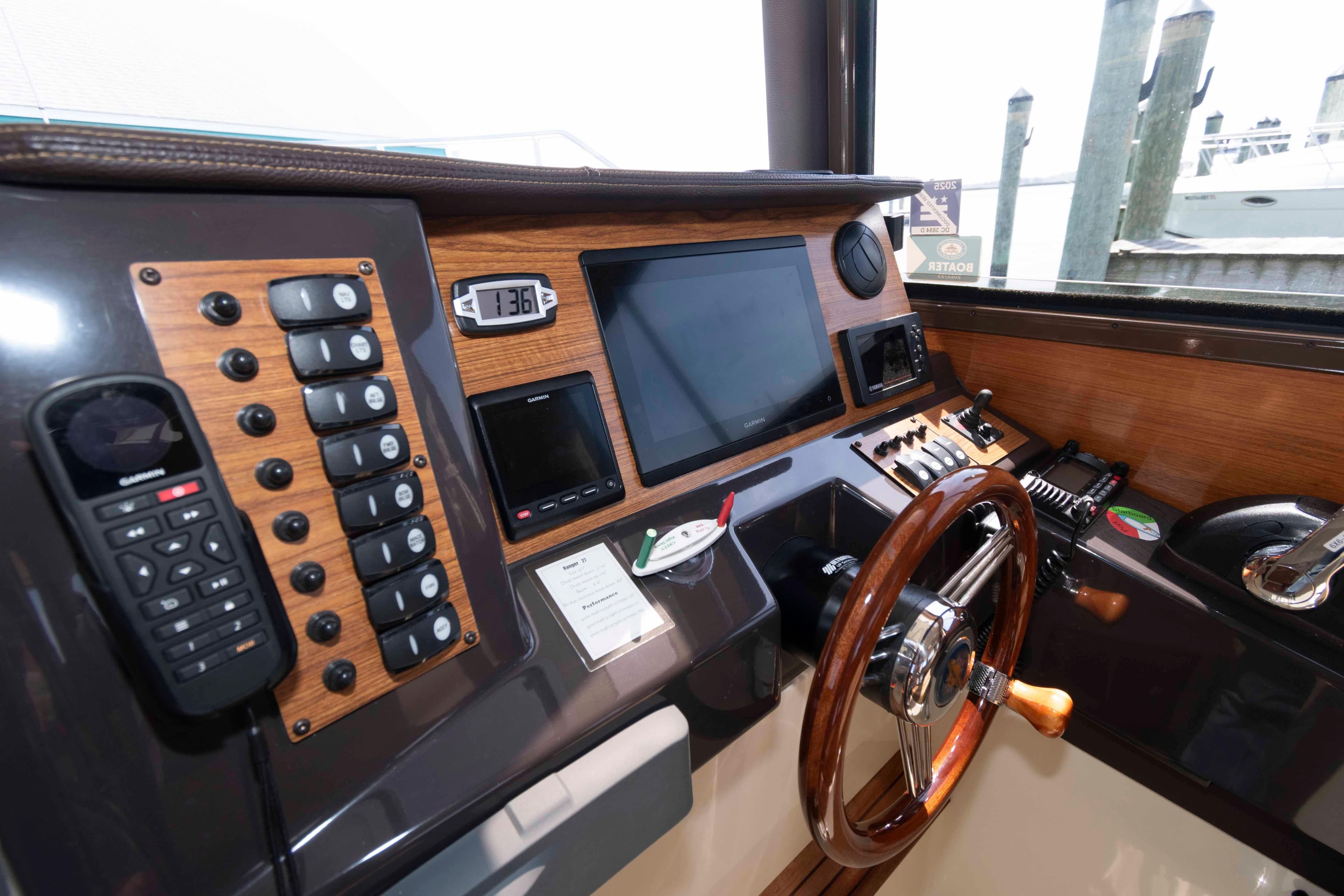 Cockpit of 2020 Ranger Tugs R-27 with navigation controls and wooden steering wheel.