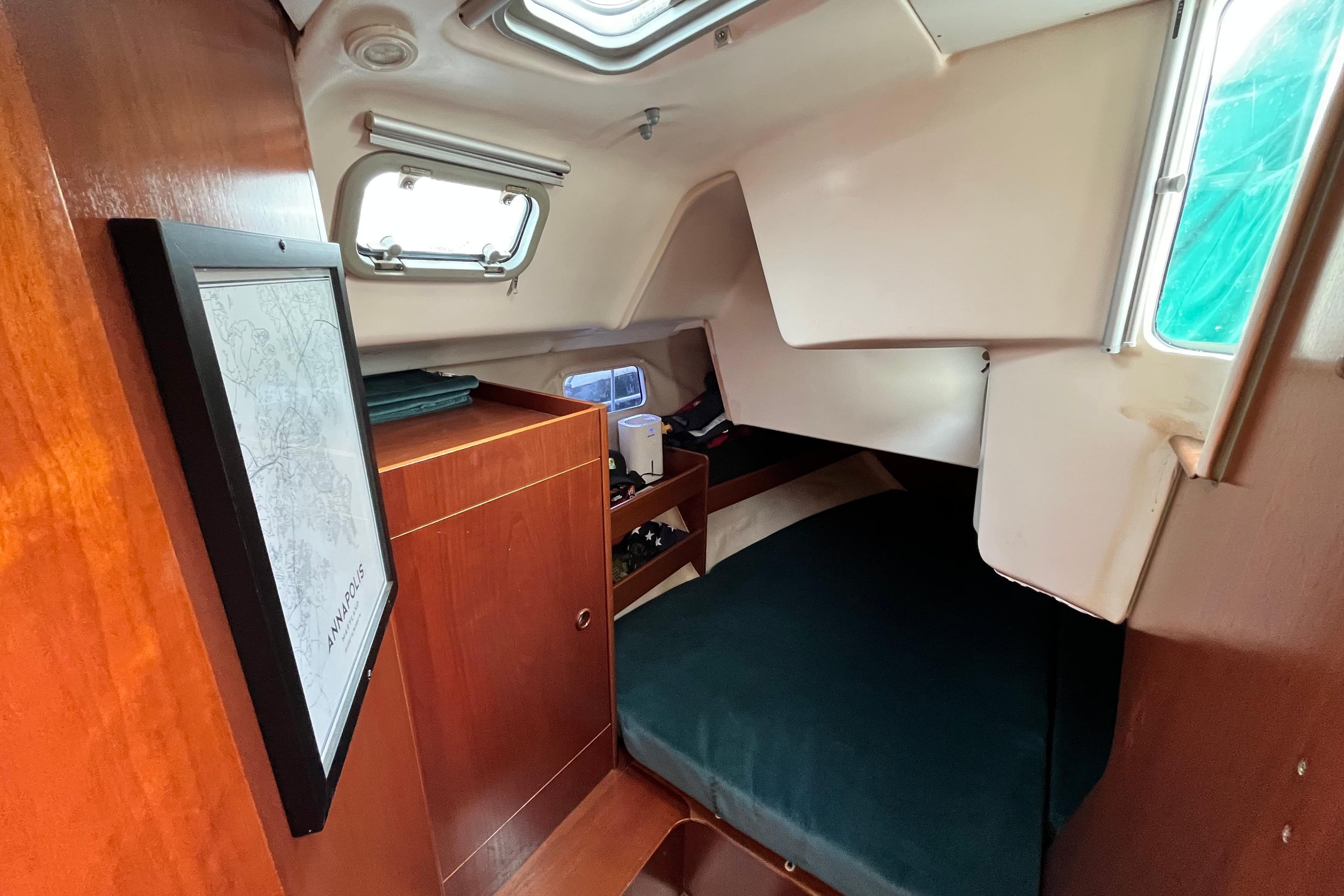 Cozy cabin interior of 1995 Beneteau Oceanis 351 sailboat with wood finish and porthole windows.