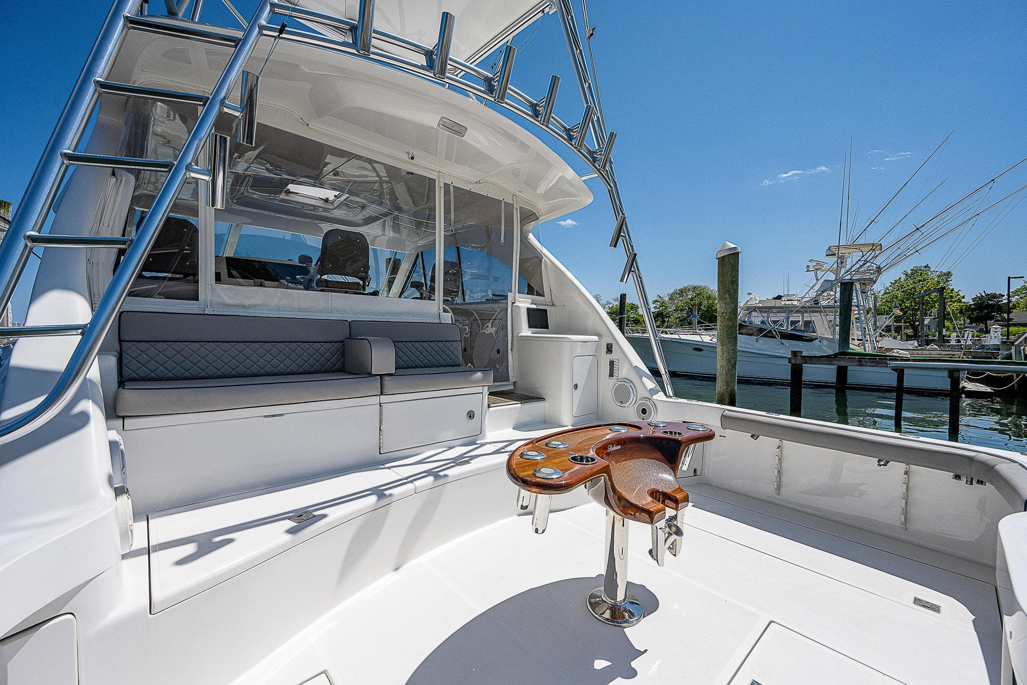 2012 Cabo 44 HTX yacht cockpit with seating and fishing chair, docked under clear blue sky.