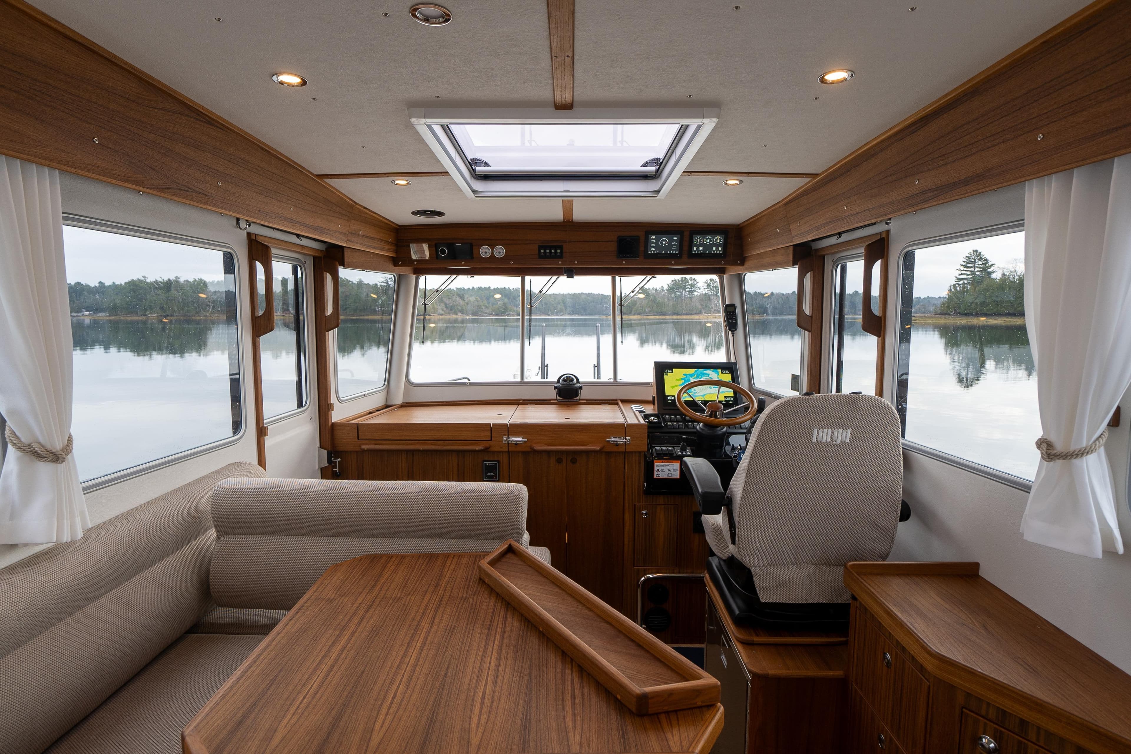 Interior of 2027 Targa 32 boat with wooden furnishings and panoramic windows.