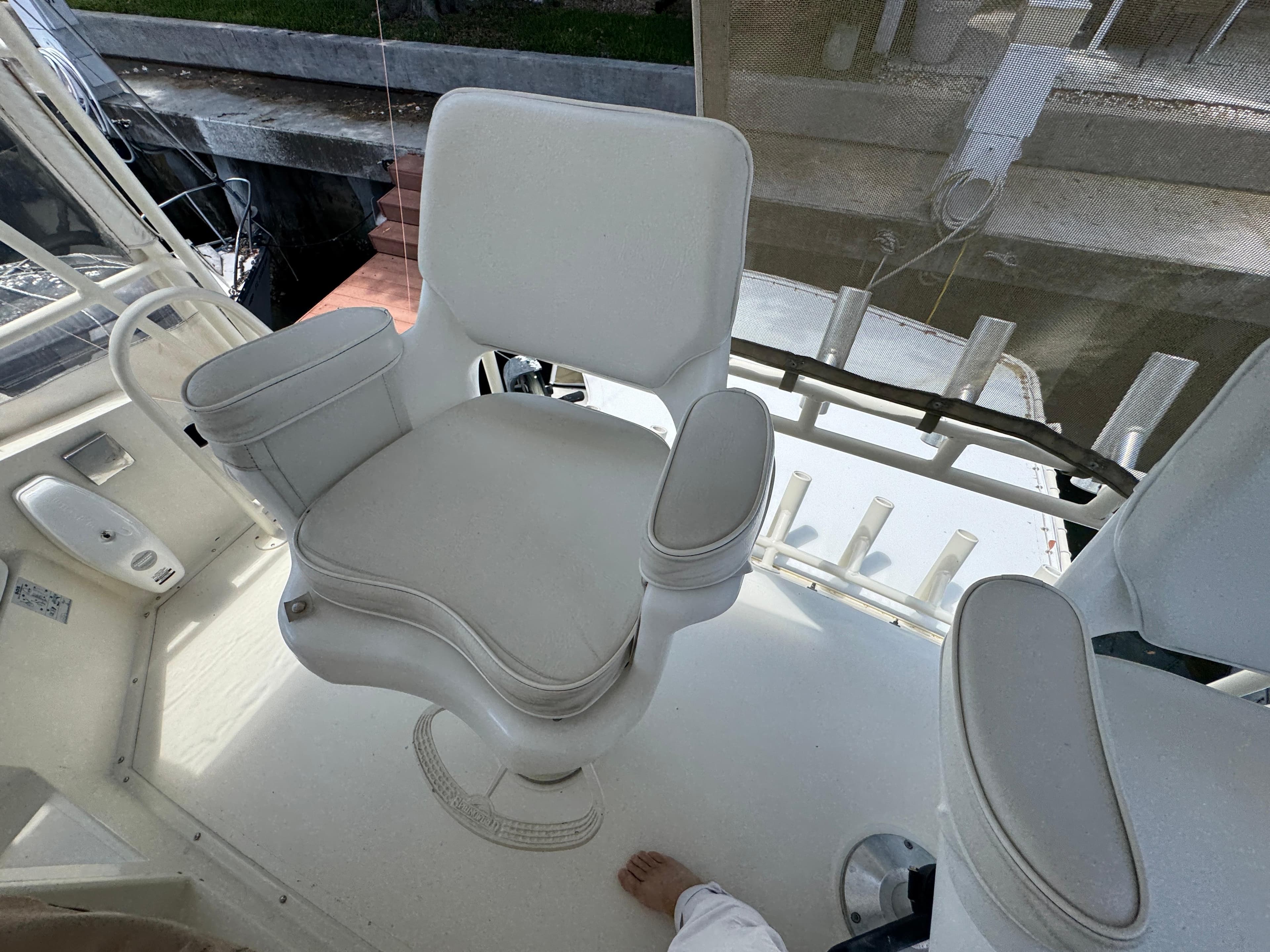 Captain's chair on a 1990 Viking 35 boat, featuring white upholstery and armrests.