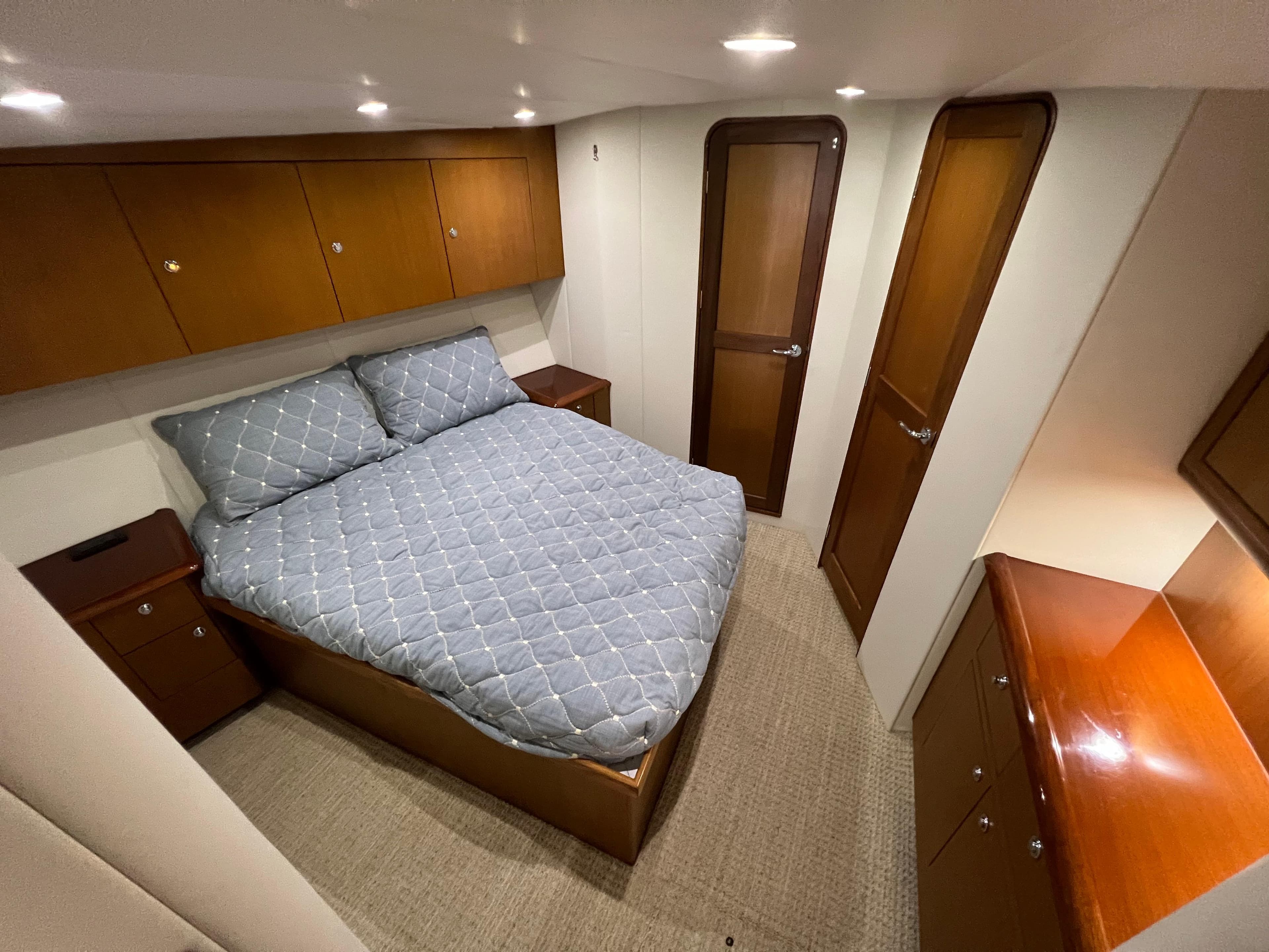 Luxurious bedroom in 2001 Ocean 52 Convertible yacht with wood cabinetry and cozy bedding.