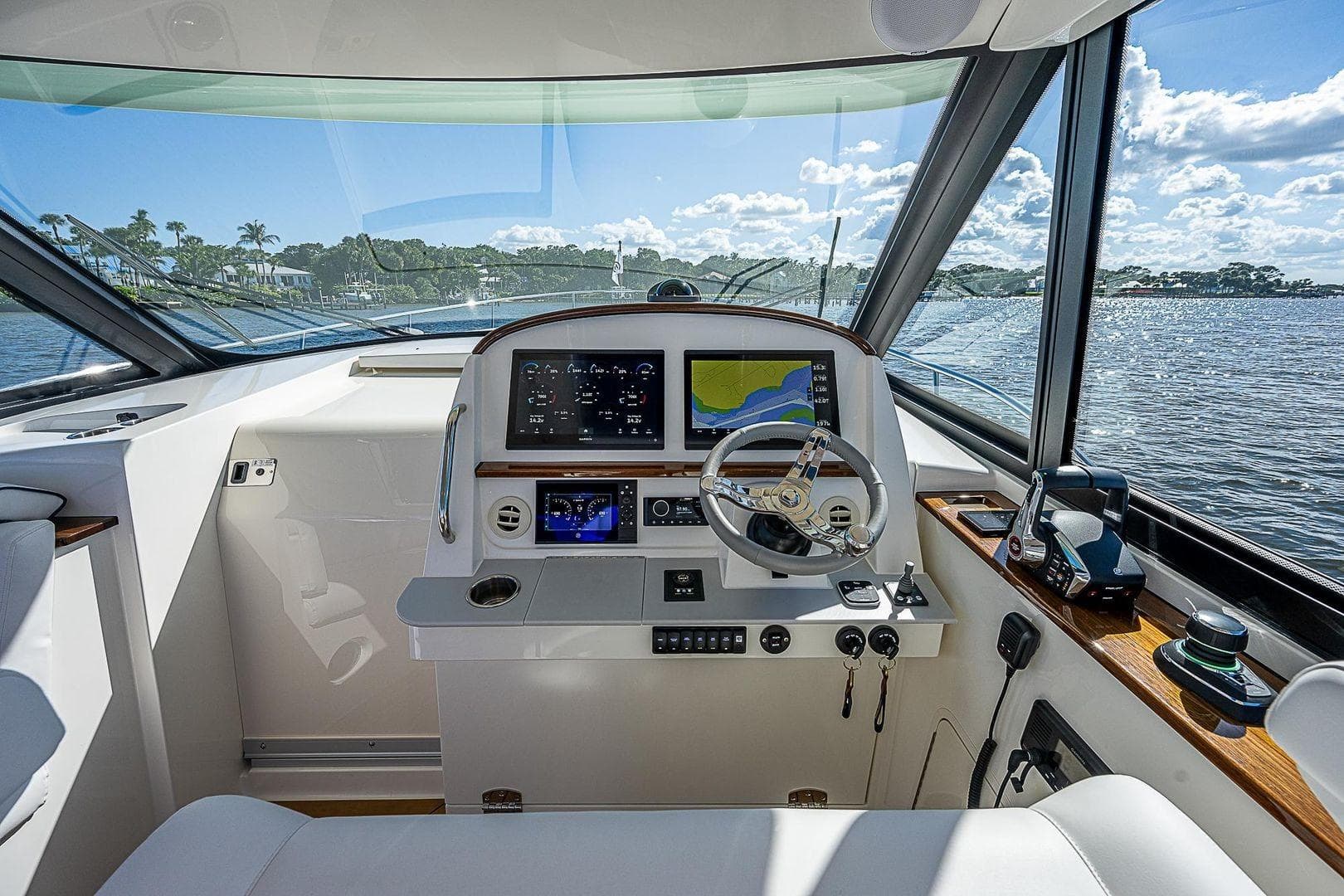 Helm of 2023 Hinckley 40x yacht with modern navigation equipment and scenic water view.