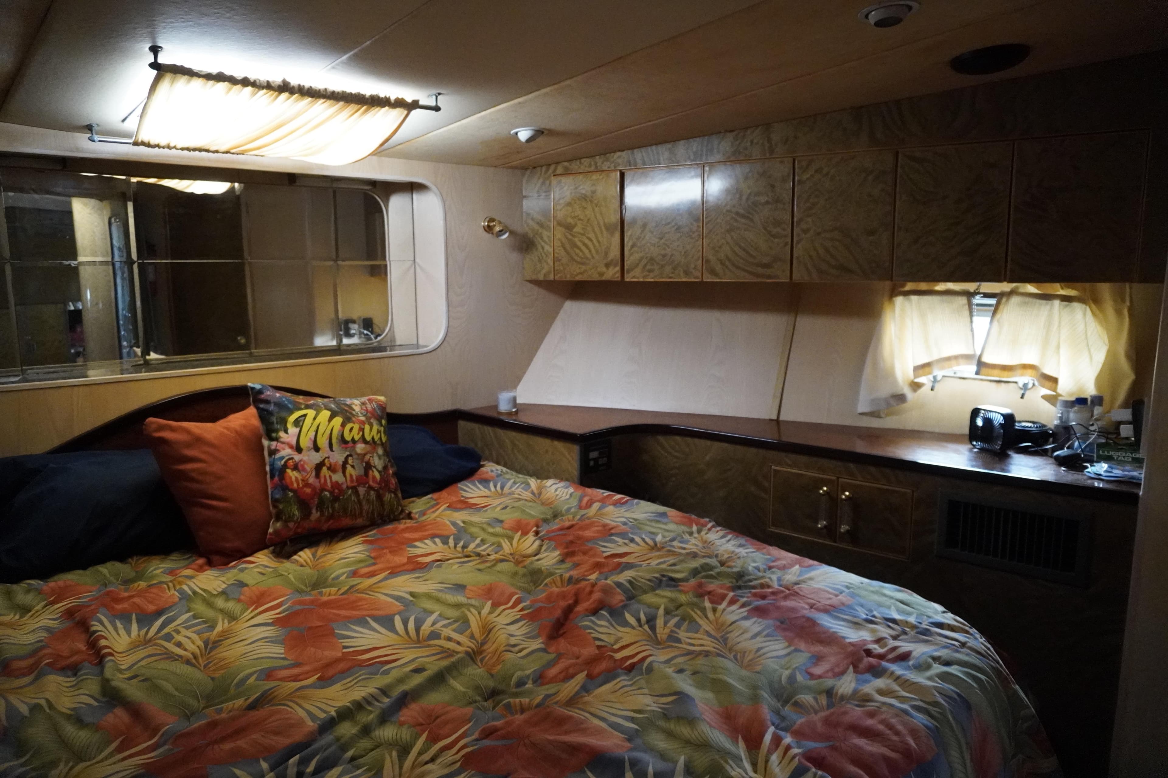 Cozy bedroom in 1992 Horizon Power Boat with tropical decor and wooden cabinetry.