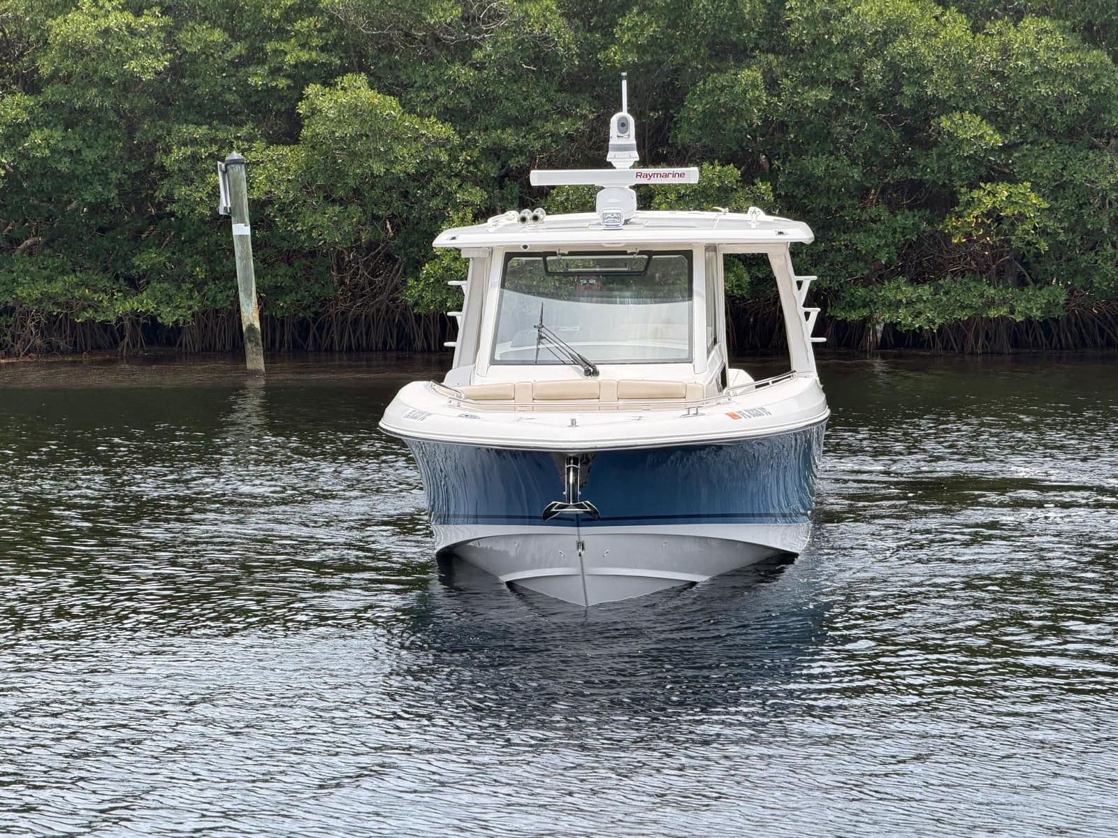2022 Boston Whaler 350 Realm on calm water near trees.