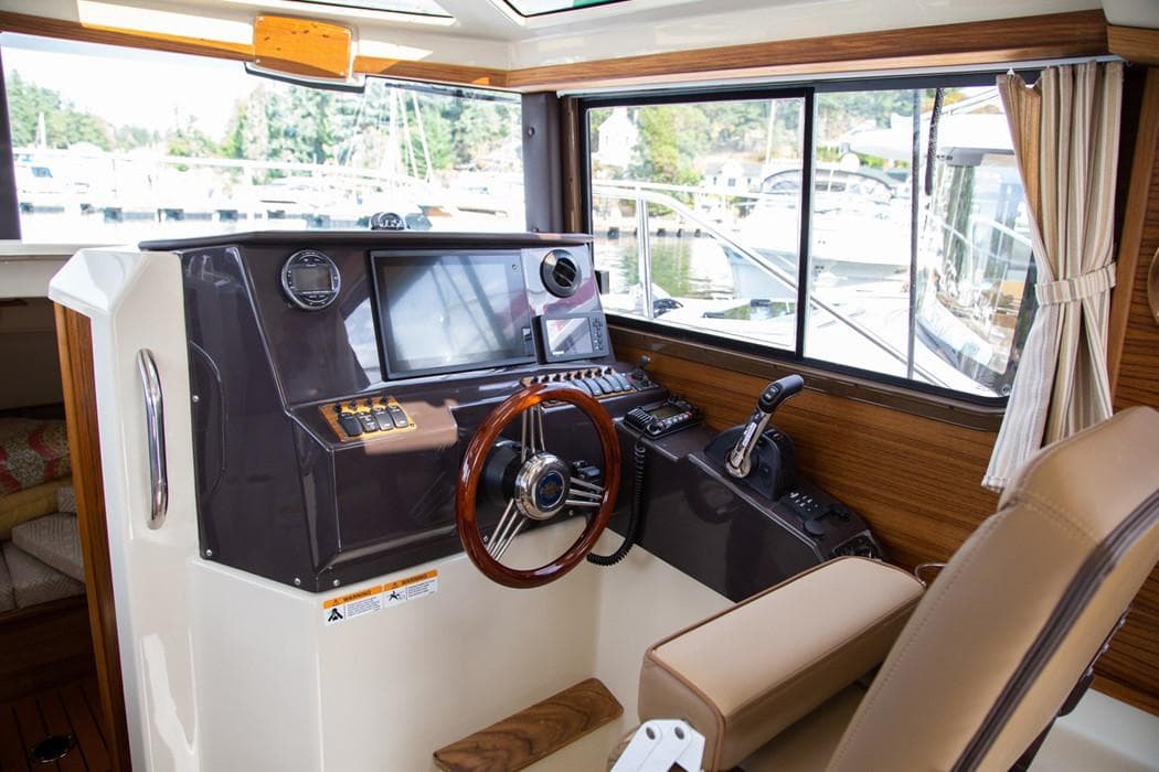 Manufacturer Provided Image: 2022 Ranger Tugs R-25 helm station with modern navigation equipment and wooden steering wheel.