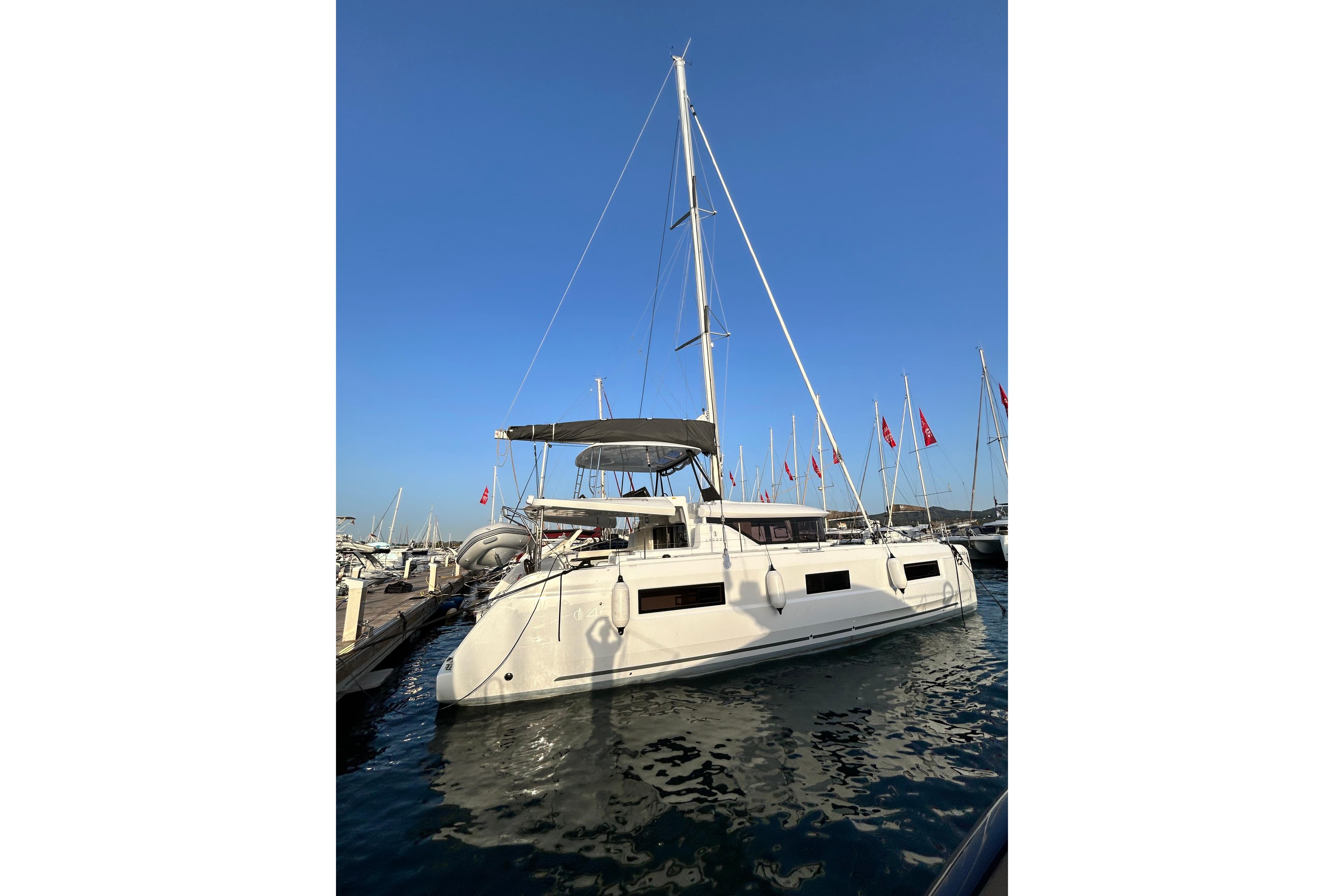 2024 Lagoon 46 catamaran docked at marina under clear blue sky.