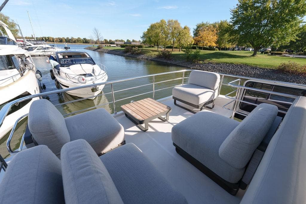 Luxurious 2022 Absolute 52 Navetta yacht with spacious outdoor seating, docked by a serene riverside.