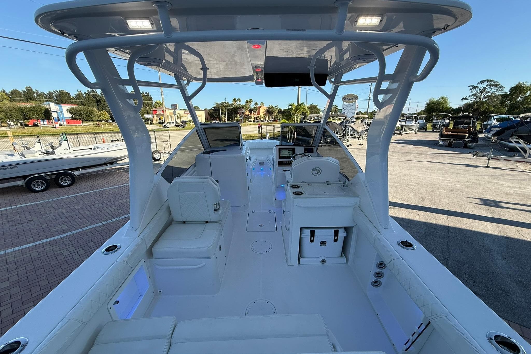 2019 Edgewater 230CX Crossover boat interior with seating and control panel in a marina setting.