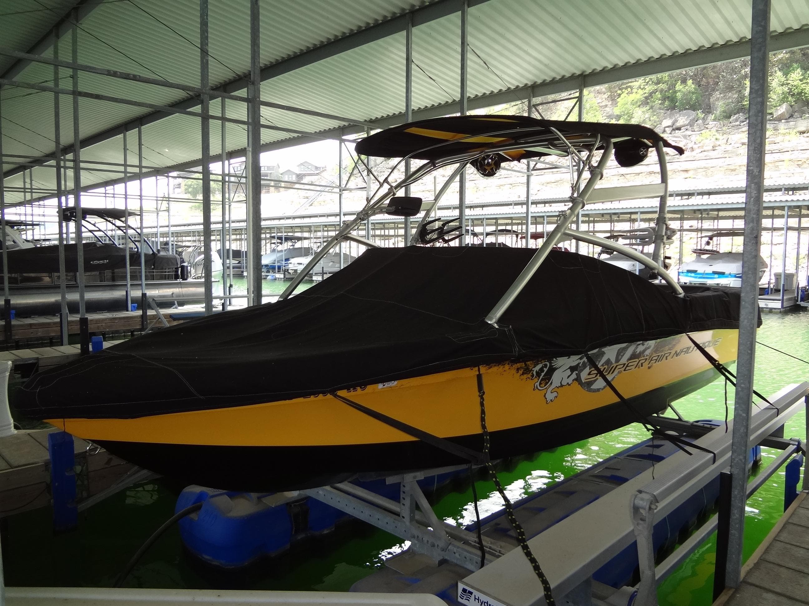 2008 Correct Craft Super Air Nautique 230 boat docked under a covered marina.