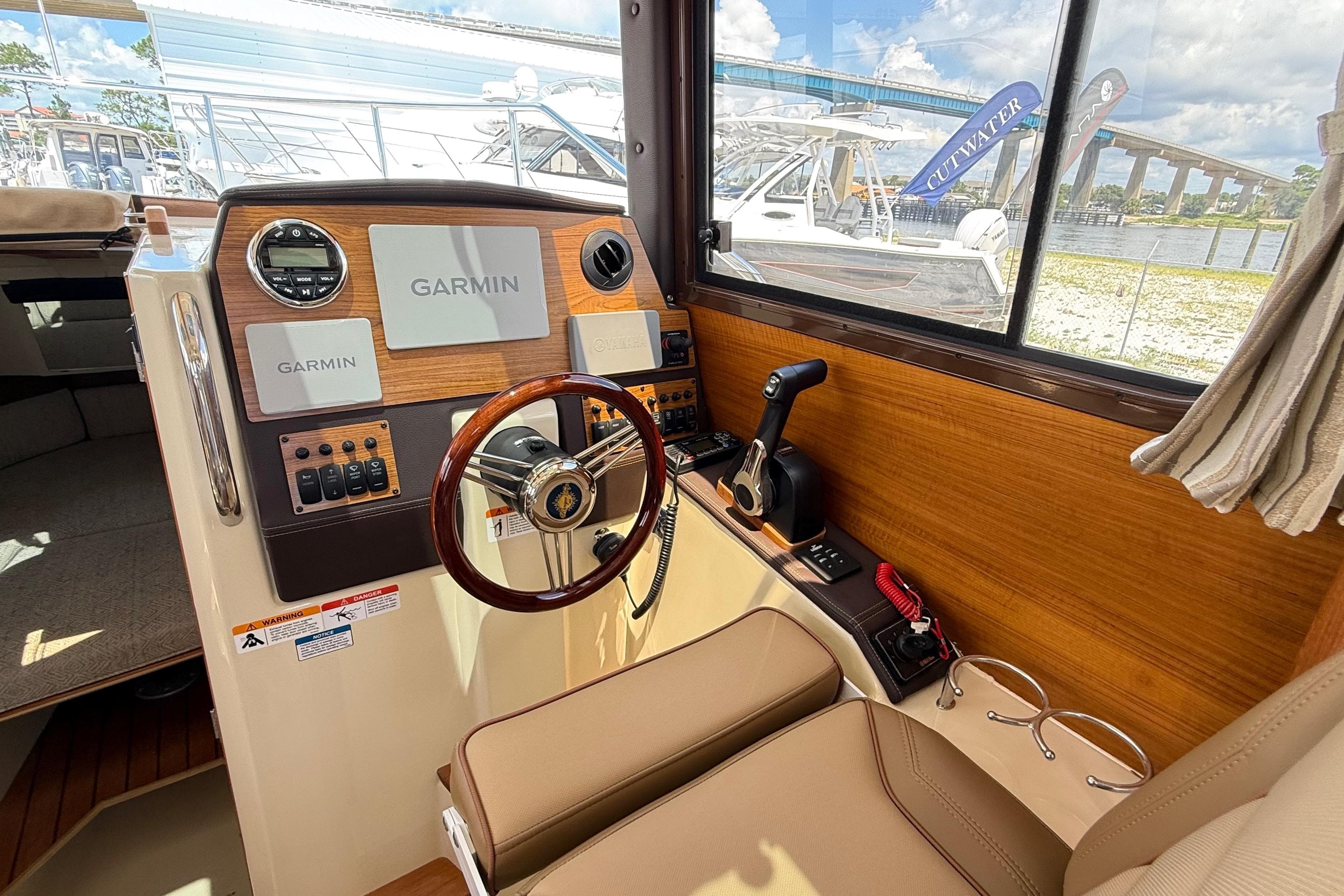 2025 Ranger Tugs R-23 helm with Garmin navigation, wood accents, and comfortable seating.