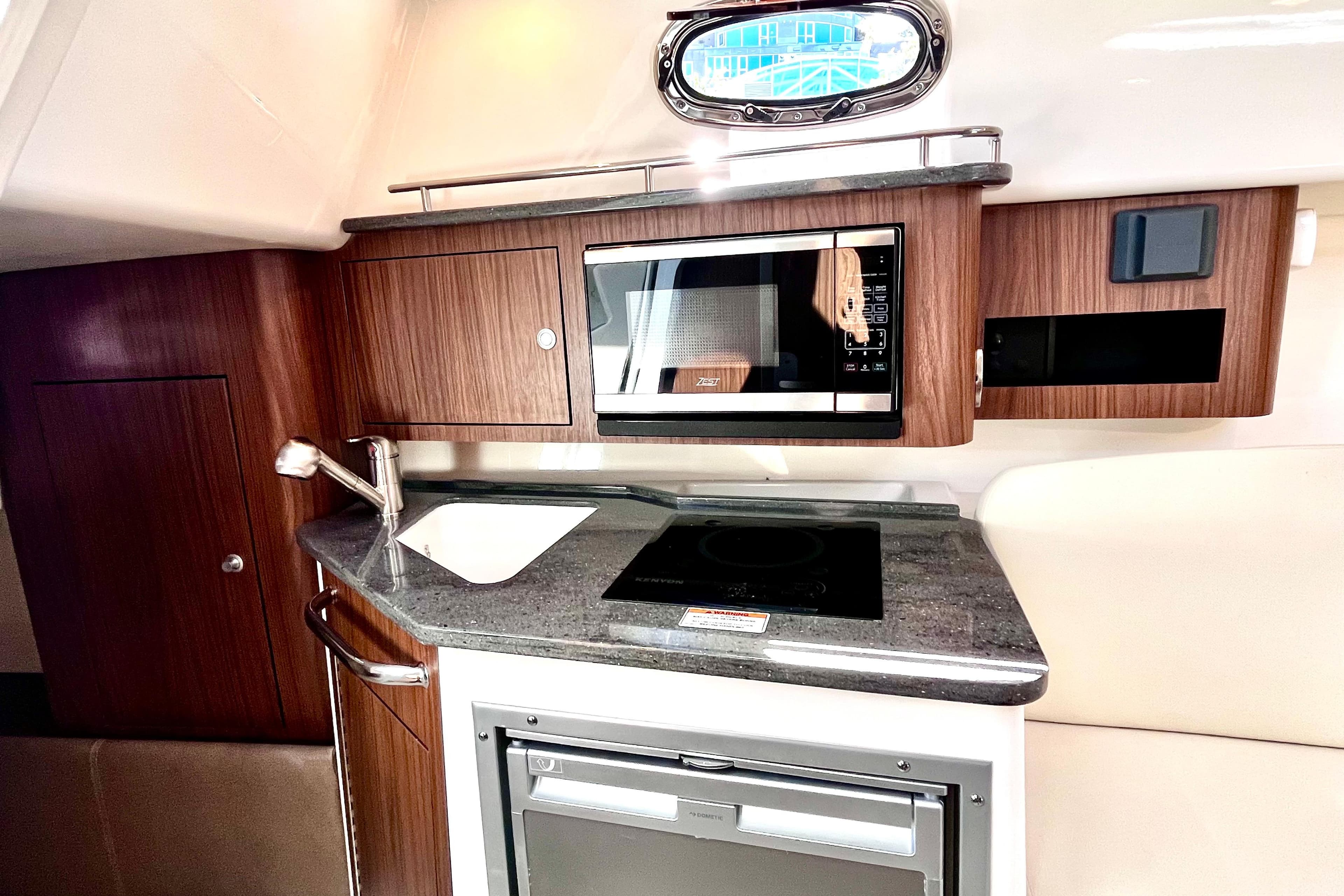 2023 Boston Whaler 285 Conquest galley with microwave, sink, and stove.