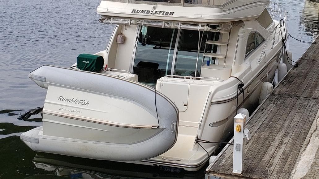 1999 Maxum 4100 SCB yacht docked with inflatable boat attached.