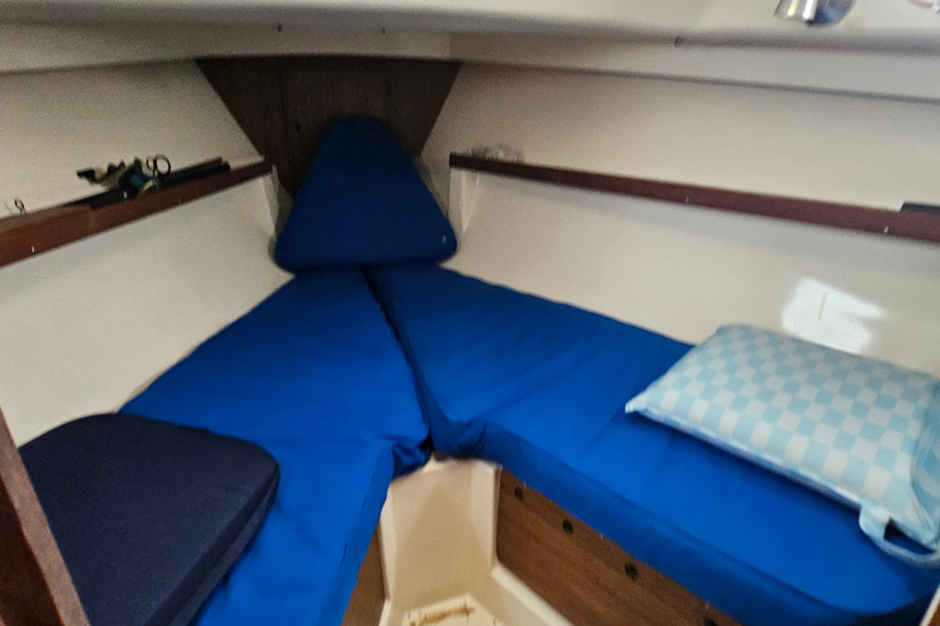 Cozy cabin interior of 1977 Seafarer 38 sailboat with blue cushions and wooden accents.