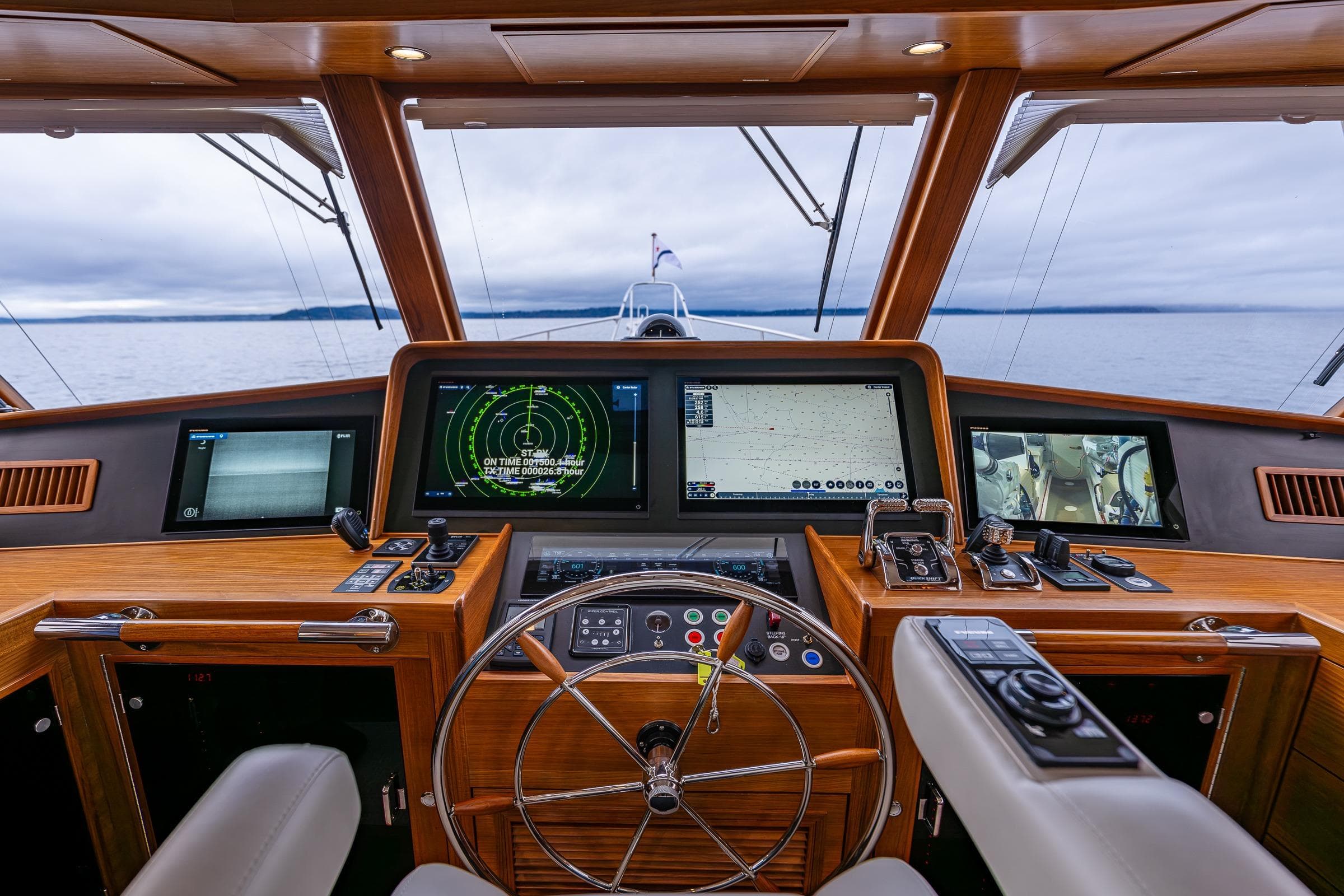 Pilothouse of 2026 Fleming 55 yacht with advanced navigation systems and steering wheel.