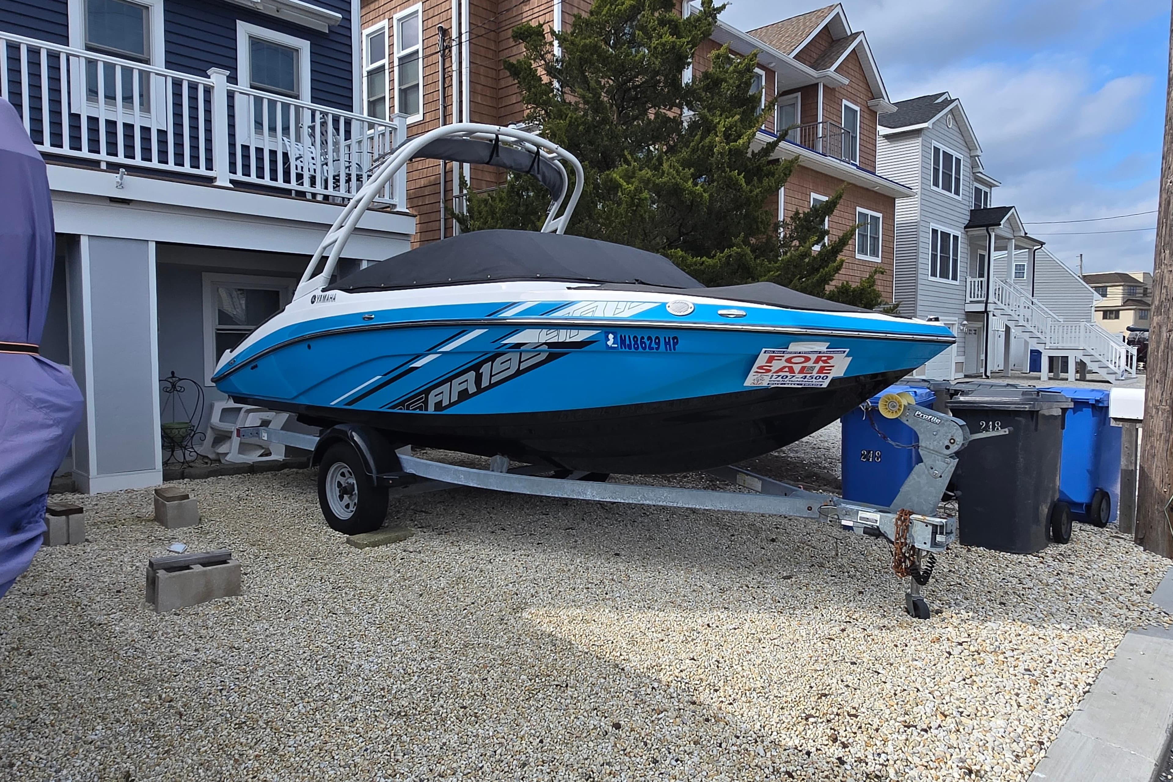 2021 Yamaha Boats AR195 for sale, parked on a trailer in a residential area.