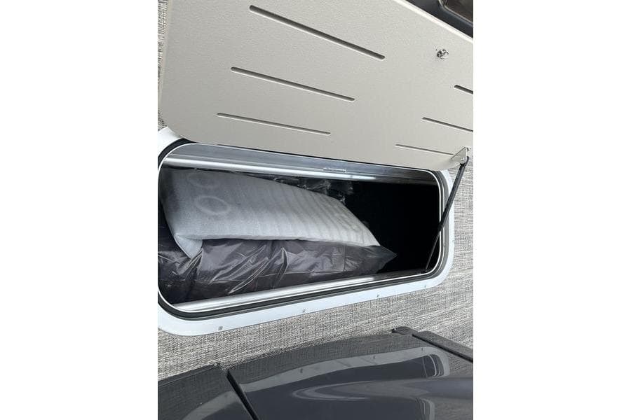 Storage compartment of 2026 Bennington M Quad Bench 24 MSL, showing interior contents.