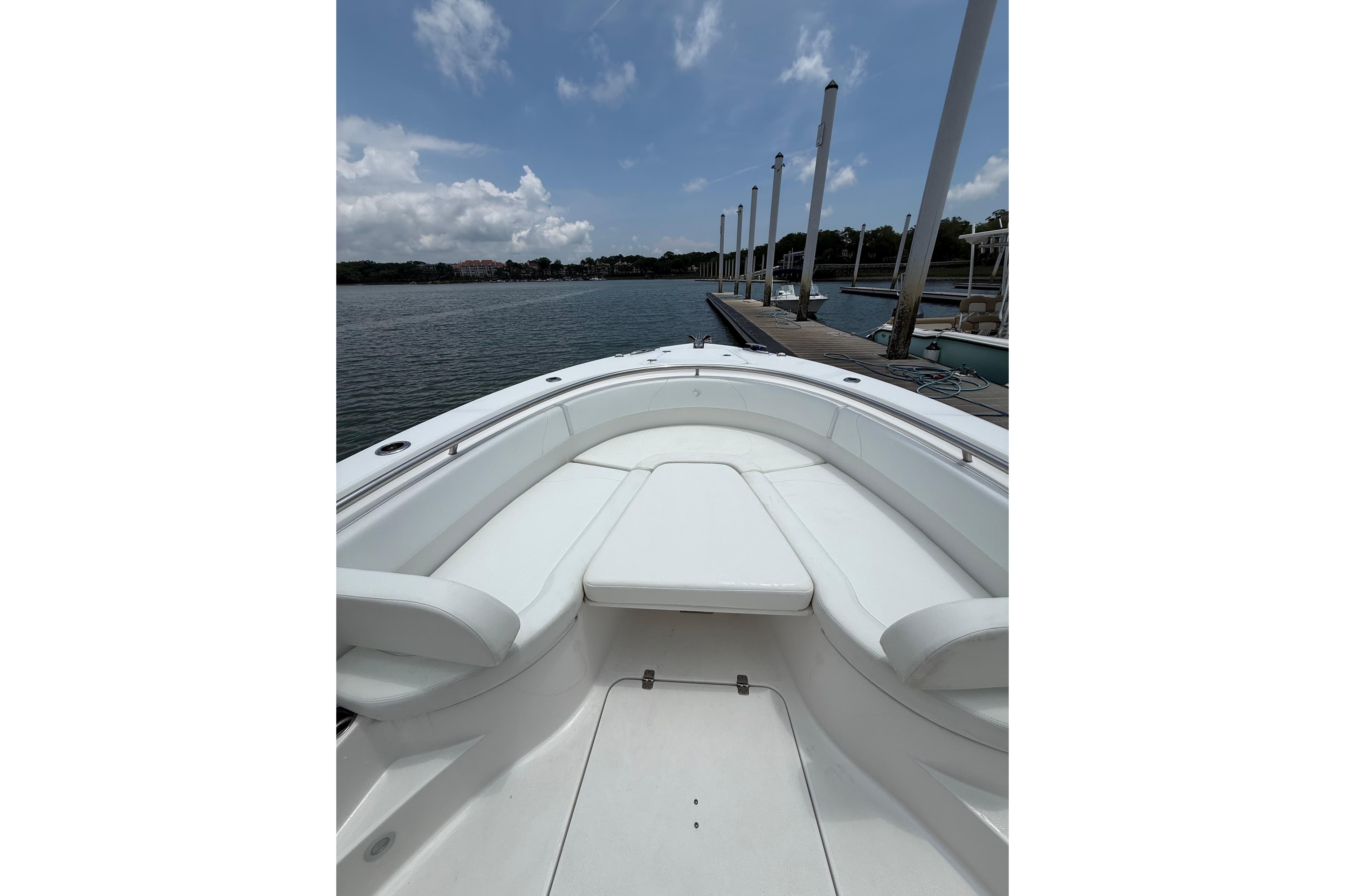 2018 Edgewater 320CC boat interior with white seating, docked by a calm waterfront.